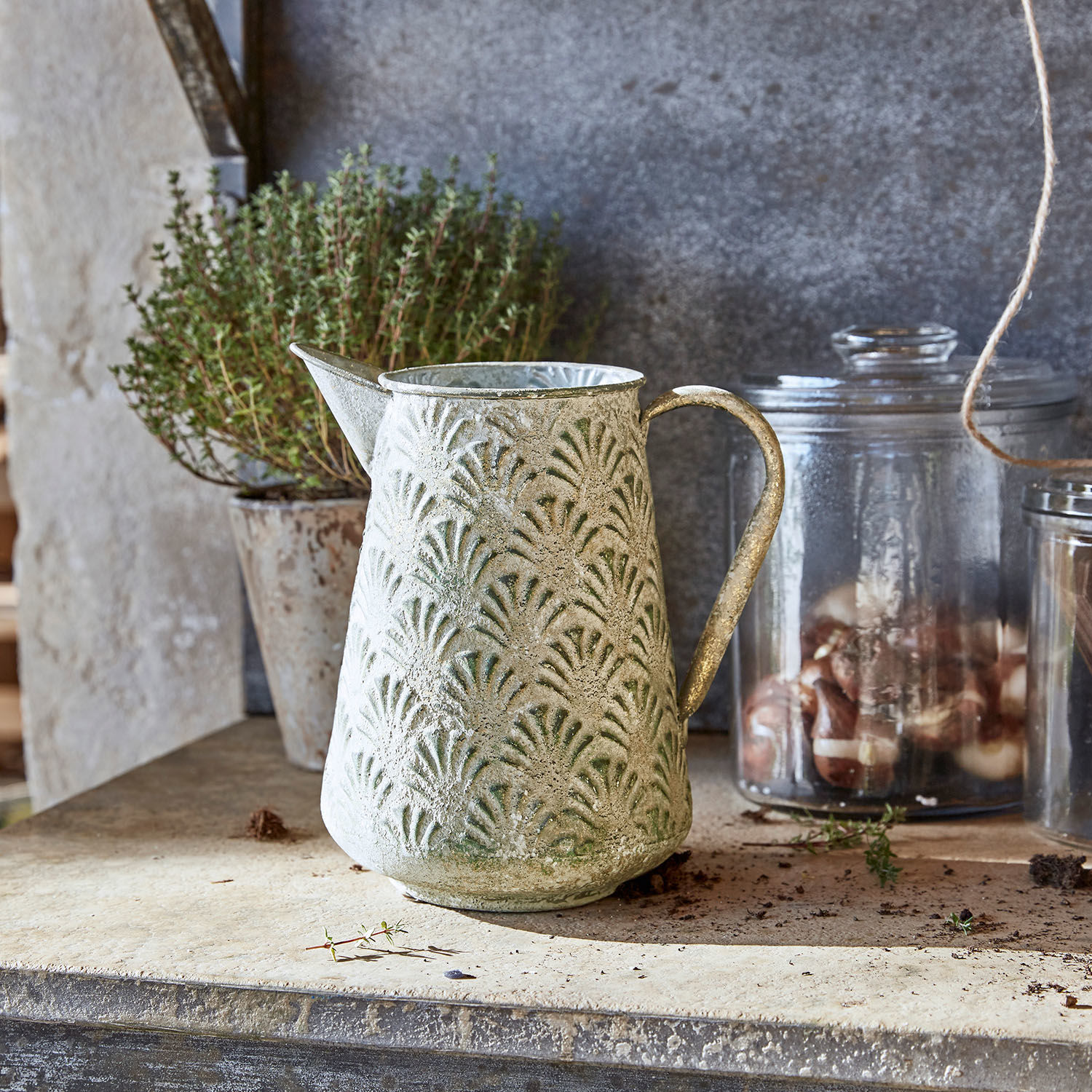 Kovová konvice se zeleným vzorem a patinou na kamenném povrchu, rustikální dekorace