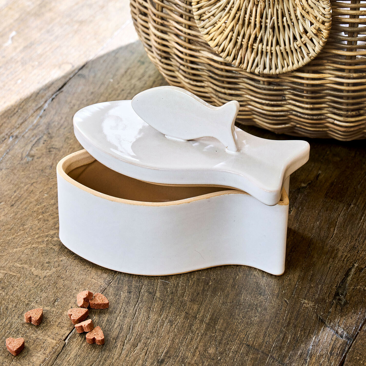 Bílá keramická dóza ve tvaru ryby s víkem na dřevěném stole, dekorace a úložný prostor