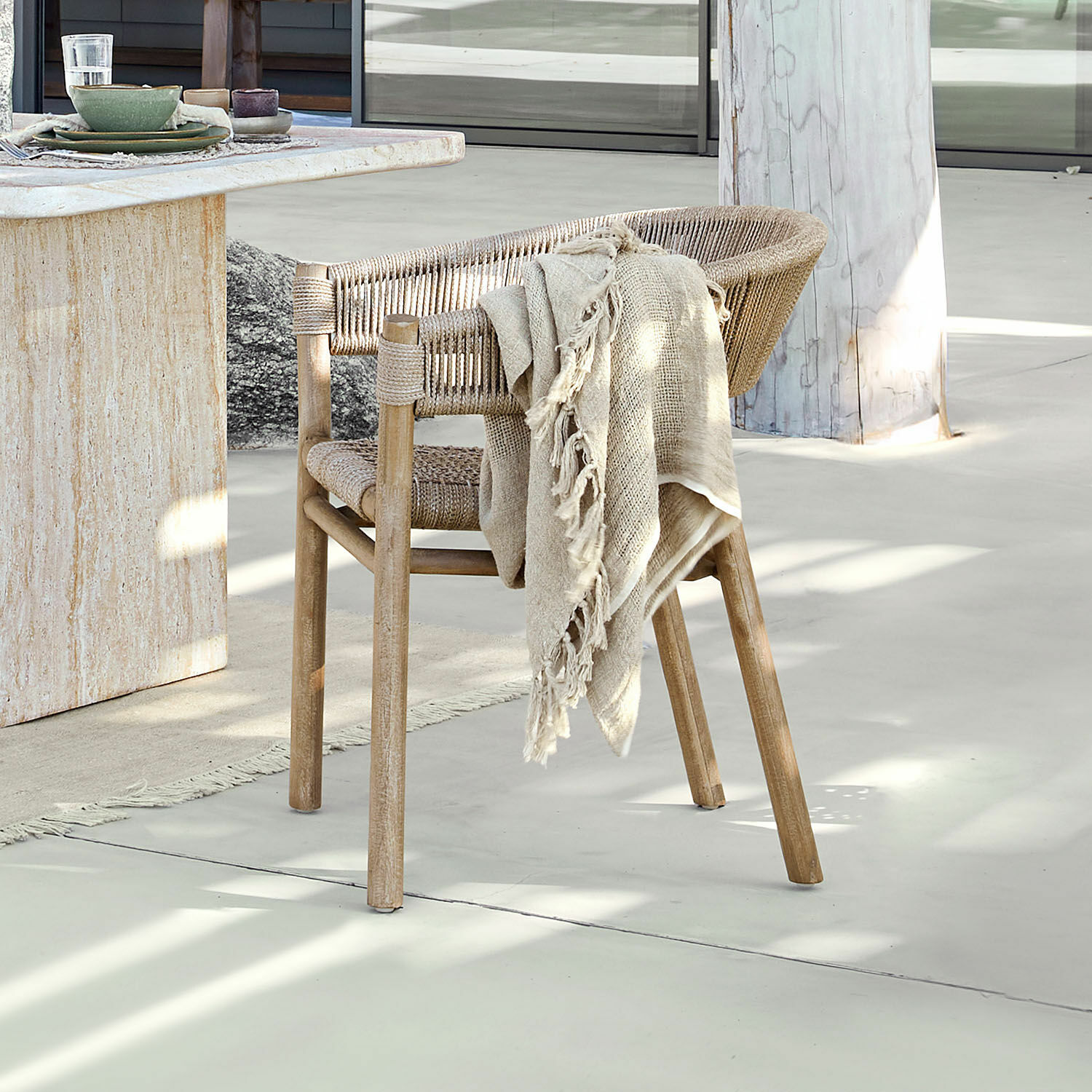 Venkovní židle FSC®-100% Garmontique Židle z dřeva a přírodního provazu v přírodní barvě s béžovou dekou na světlé podlaze u stolu