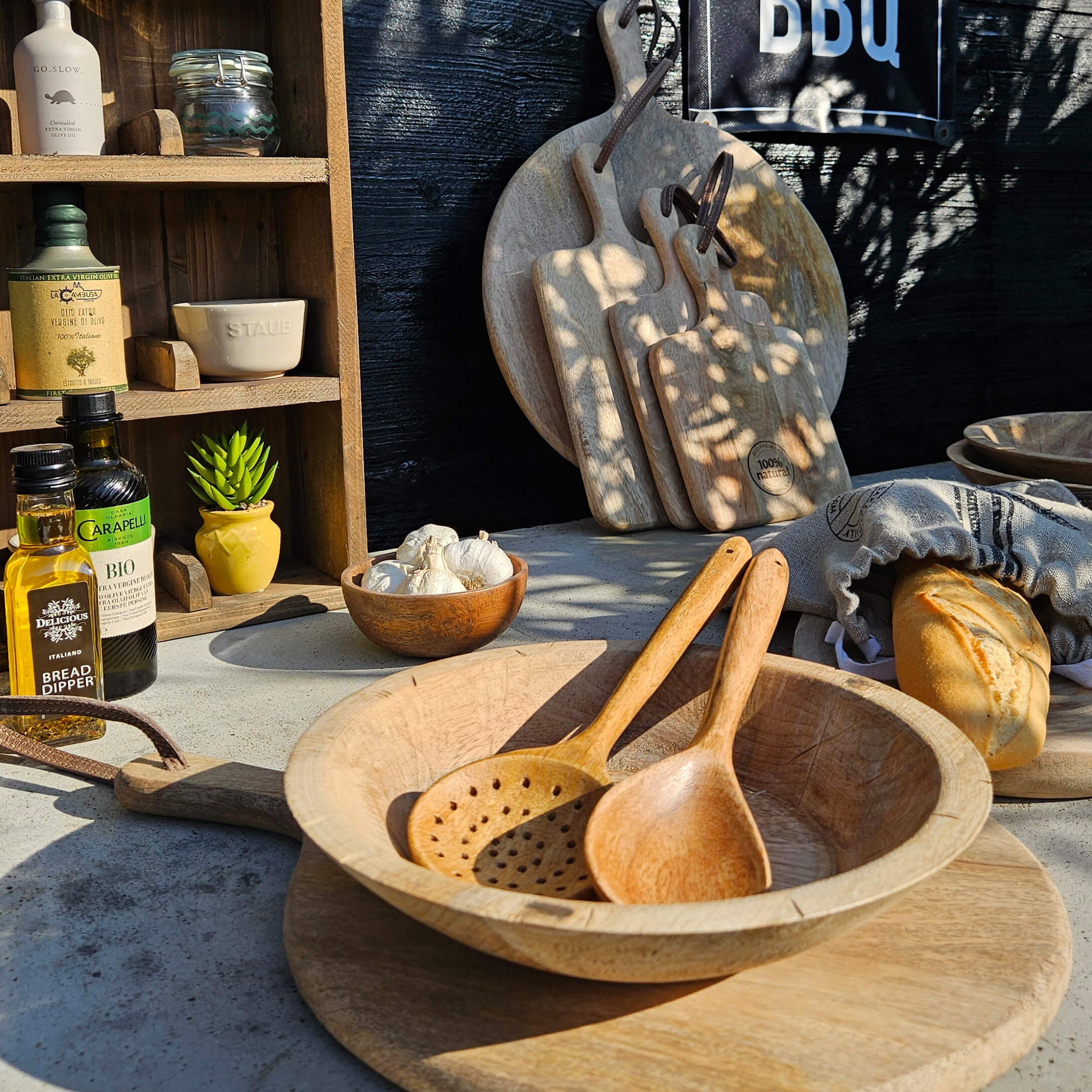 Sada dřevěných prkének a vařeček na stole s chlebem a olivovým olejem