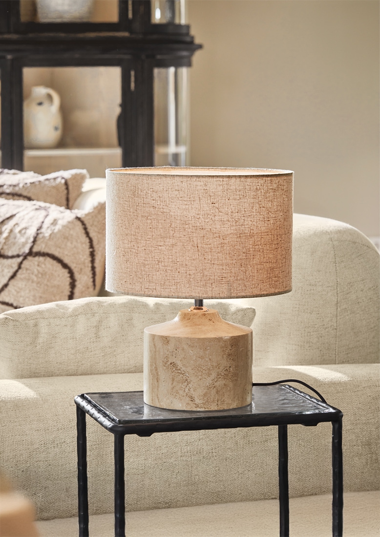 Stolní lampa s béžovým stínidlem a keramickou pískovou základnou na černém stolku