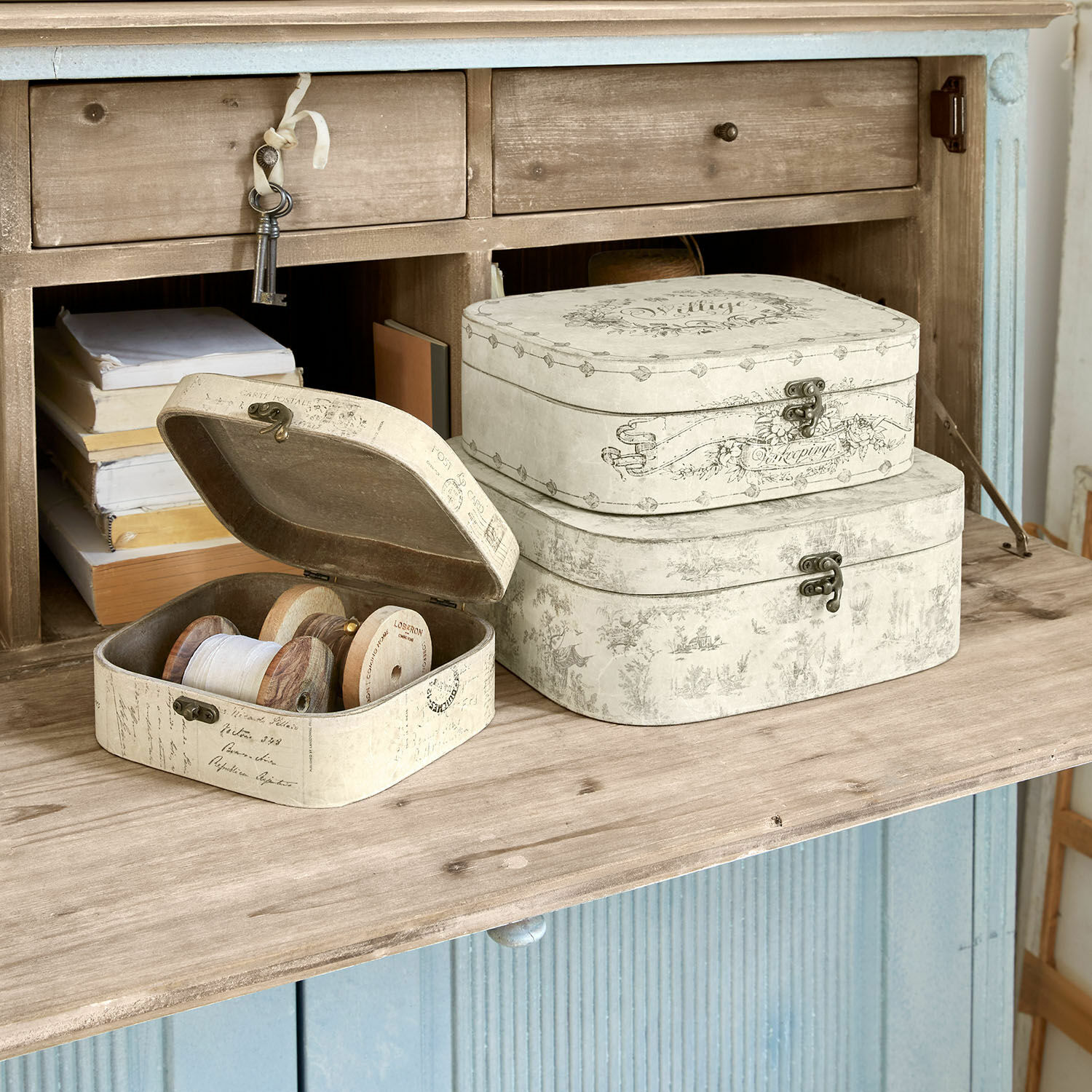 Sada tří krémových dekorativních krabic s kovovými zapínáními na dřevěném povrchu