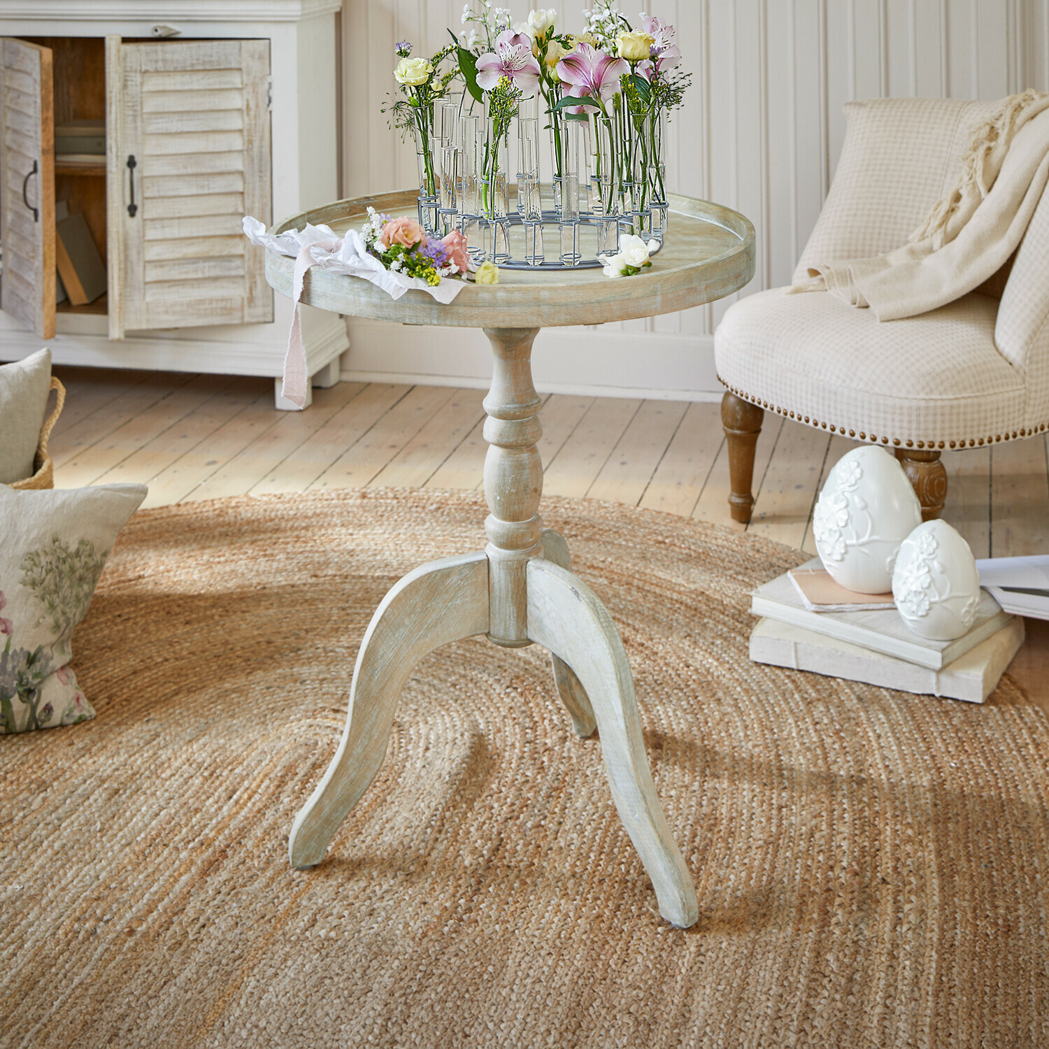 Odkládací stolek Brookdale Kulatý dřevěný stolek ve světlém vintage stylu s květinovou dekorací na desce v obývacím pokoji