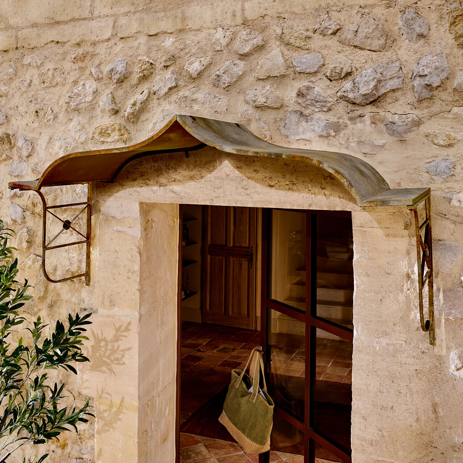 Rustikální kovová stříška nad vchodem z kamenné zdi, ochrana proti dešti