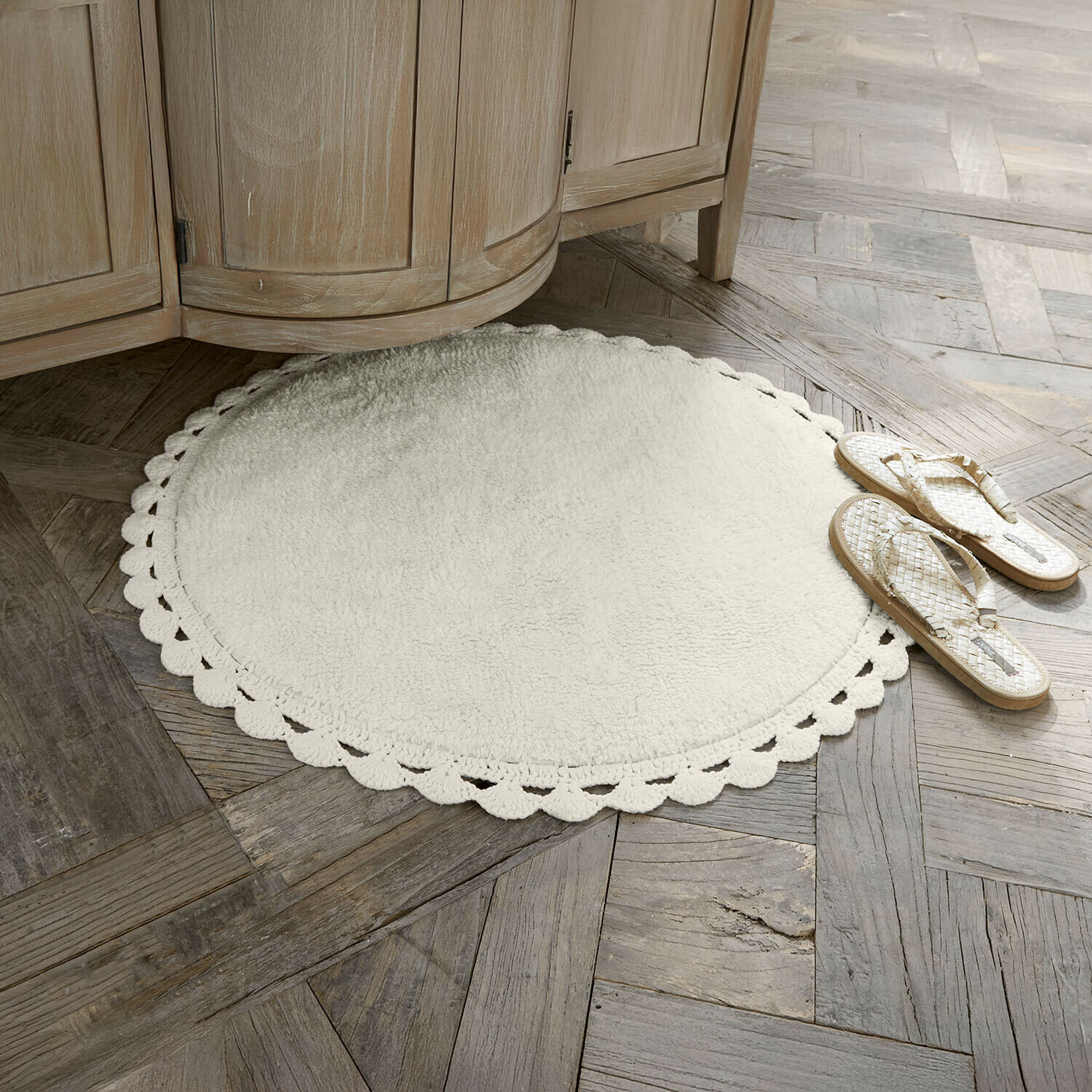 Předložka do koupelny Domévine Kulaty bílý koberec z měkkého materiálu s ozdobným okrajem na dřevěné podlaze