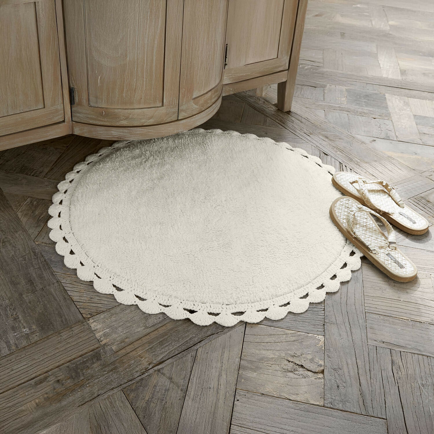 Předložka do koupelny Domévine Kulaty bílý koberec z měkkého materiálu s ozdobným okrajem na dřevěné podlaze