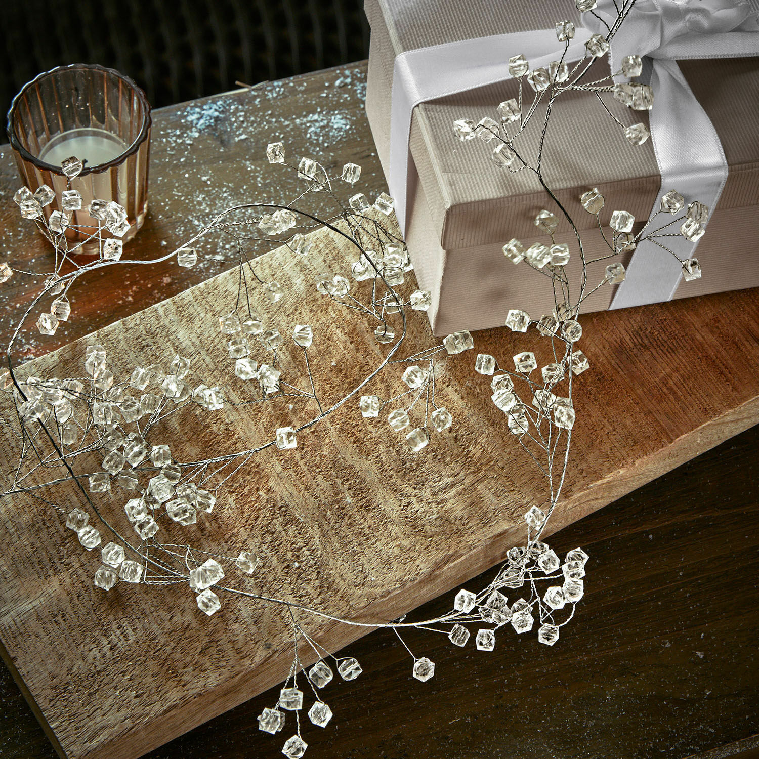 Girlanda Claix Jemný dekorativní věnec z průhledných krystalů na drátěném rámu na dřevěném stole