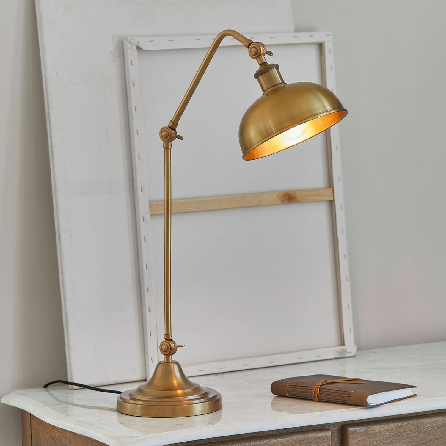 Stolní lampa Delacroille Mosazná stolní lampa s nastavitelným ramenem na mramorovém stole, vintage styl