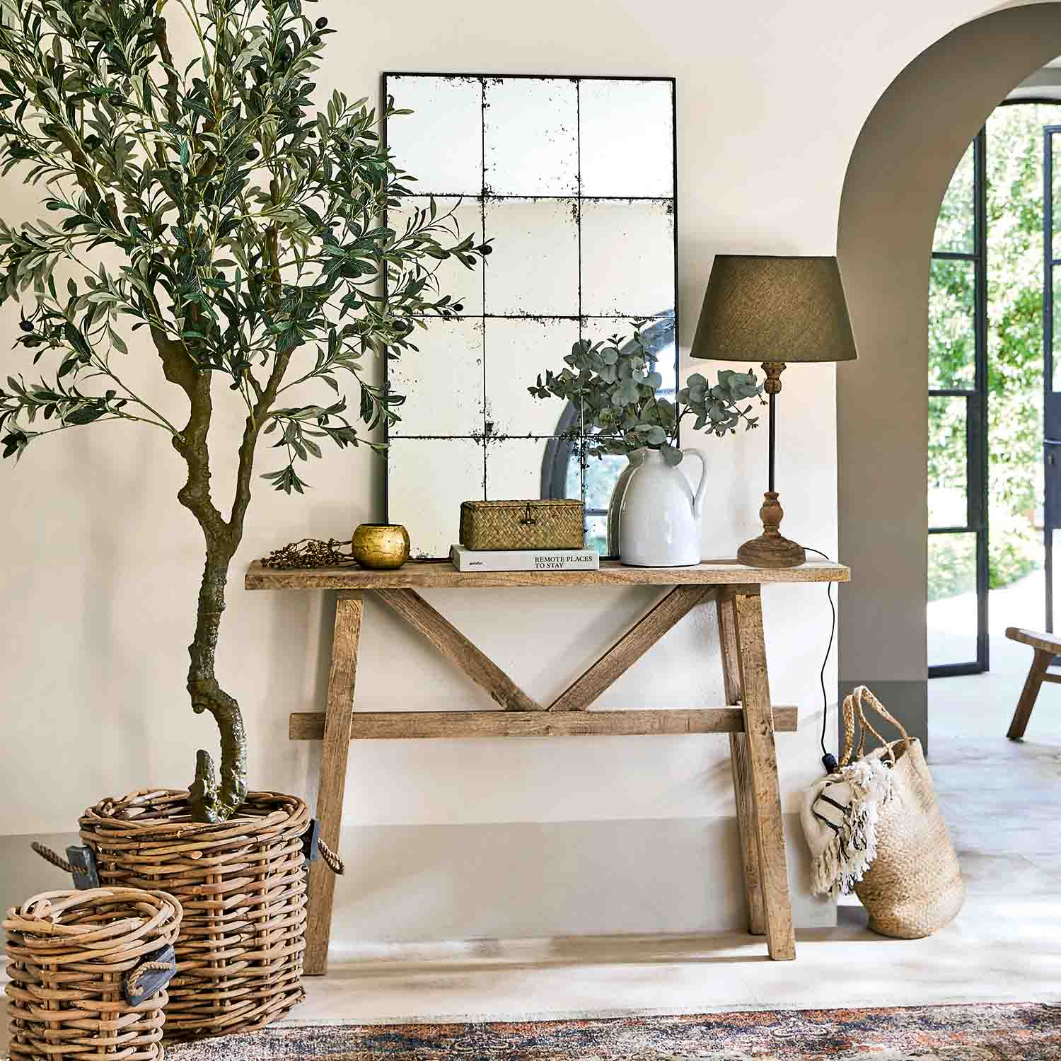 Dřevěná konzolová stůl se zrcadlem, lampou a proutěnými dekoracemi v světlém interiéru