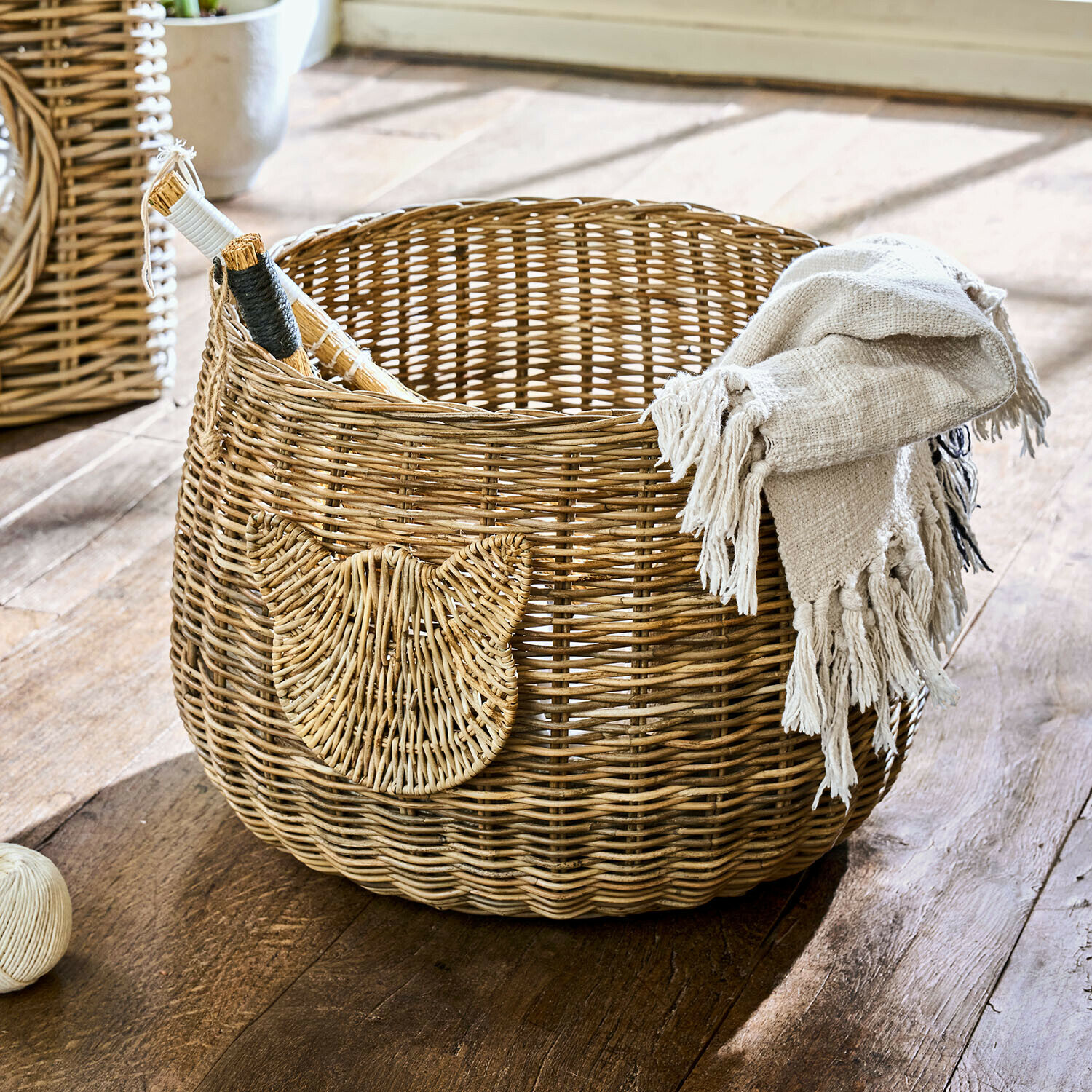 Kulatý koš z přírodního ratanu s ozdobou ve tvaru kočky a béžovou dekou