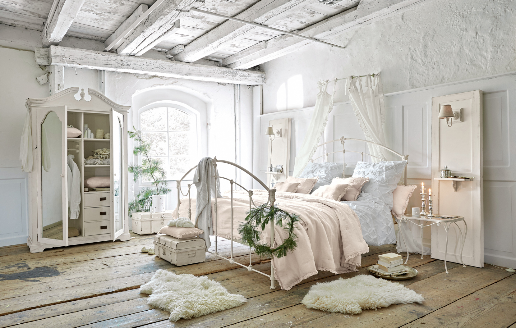 Ložnice ve stylu shabby chic s bílou kovovou postelí a pastelovým povlečením na dřevěné podlaze