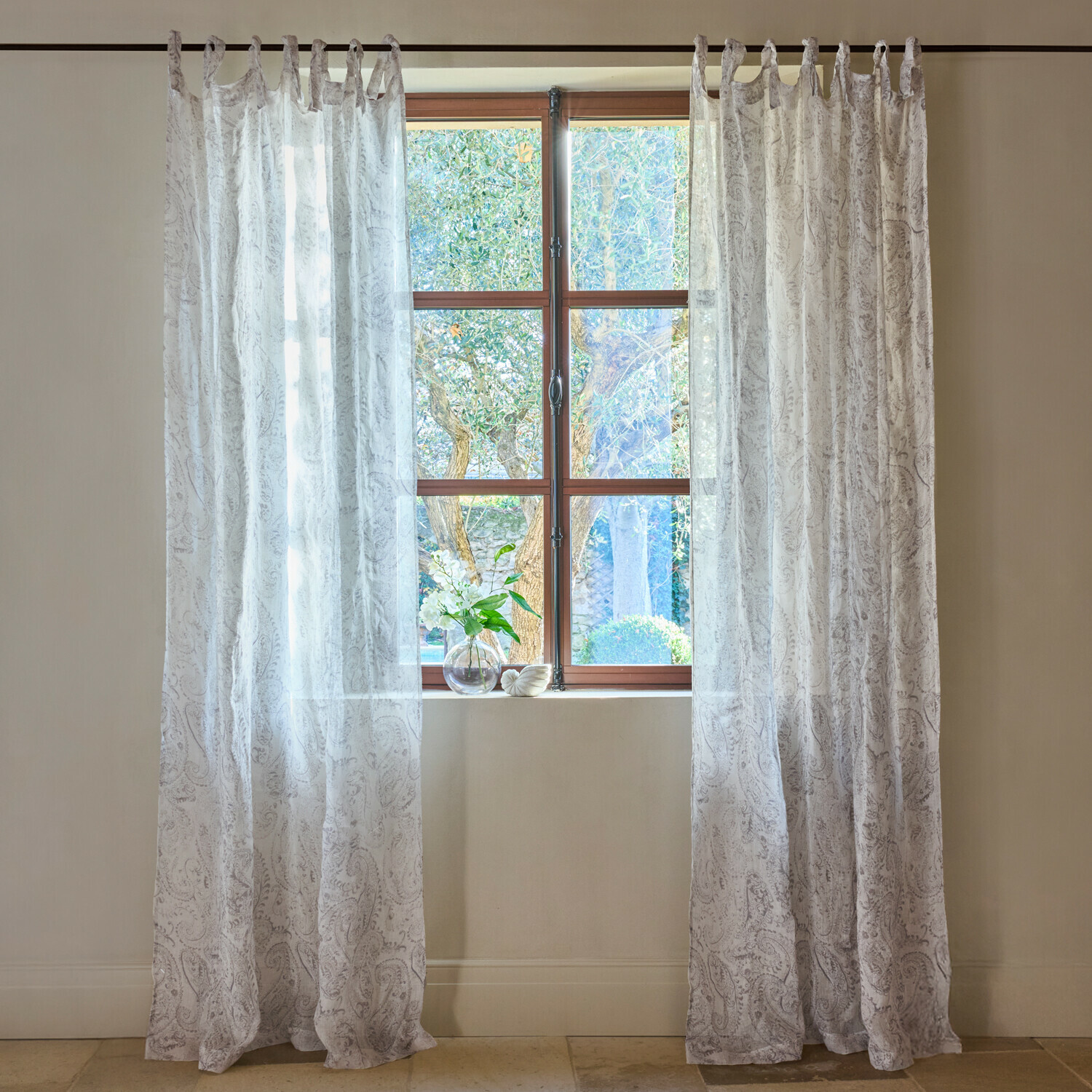 Průsvitné bílé závěsy s jemným vzorem paisley na okně, světlá interiérová dekorace