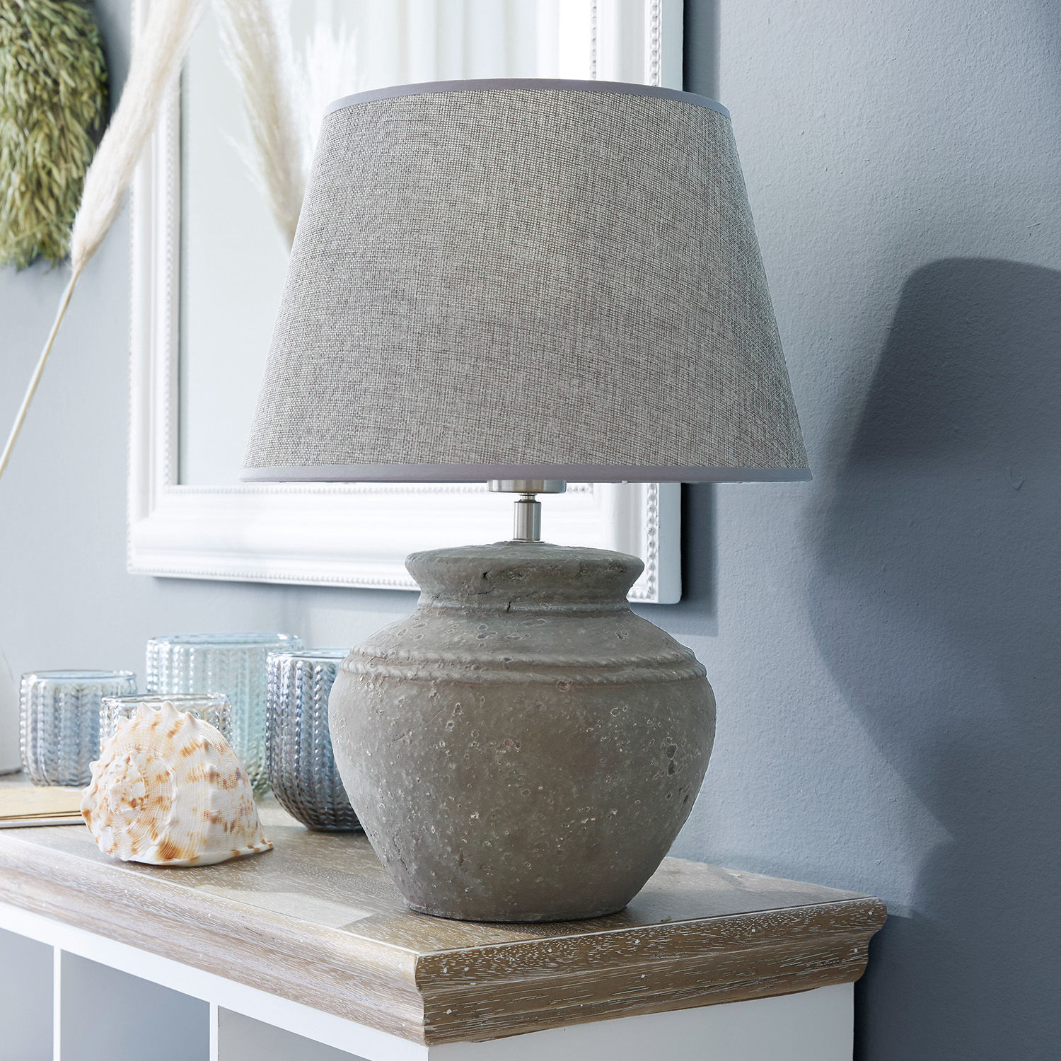 Stolní lampa Cleveland Stolní lampa se šedou keramickou základnou a béžovým stínidlem na dřevěném povrchu