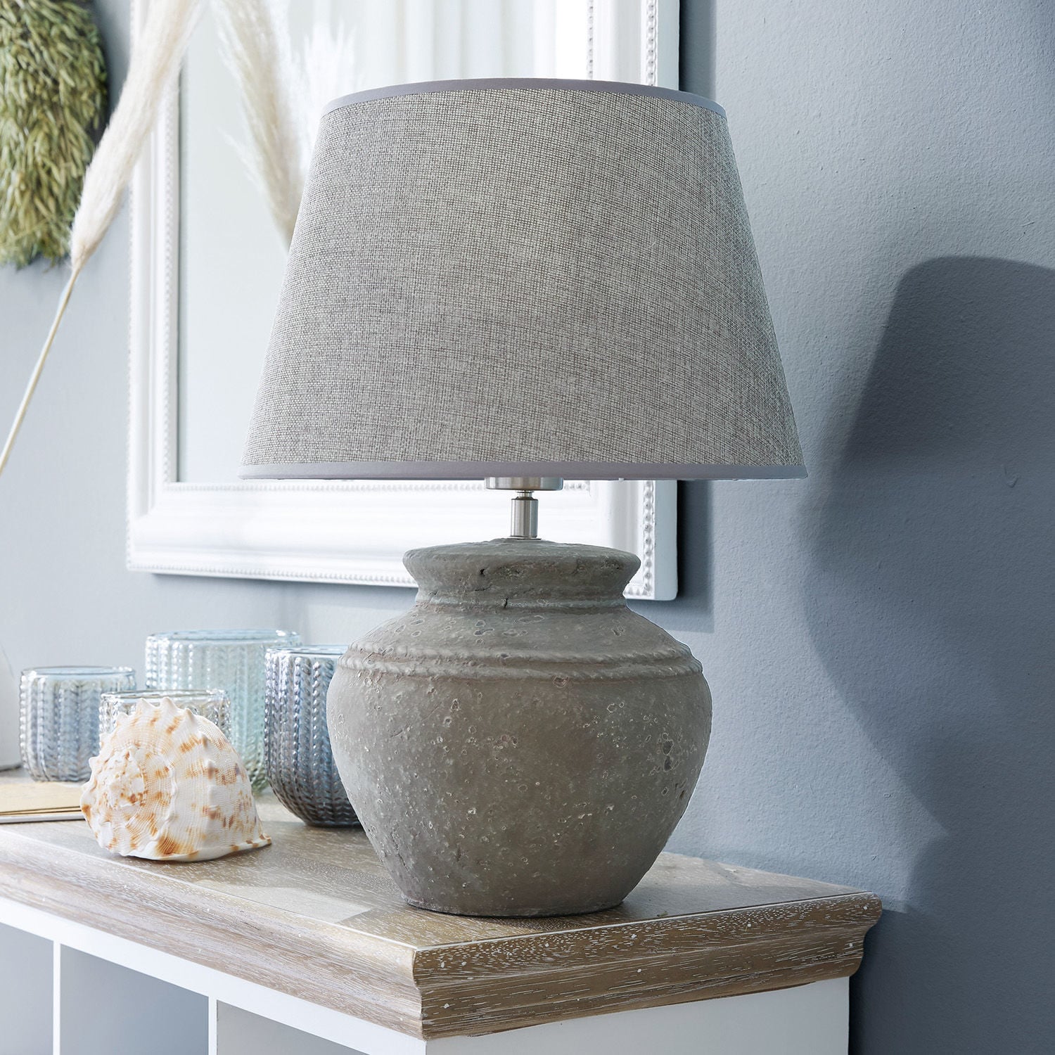 Stolní lampa Cleveland Stolní lampa se šedou keramickou základnou a béžovým stínidlem na dřevěném povrchu