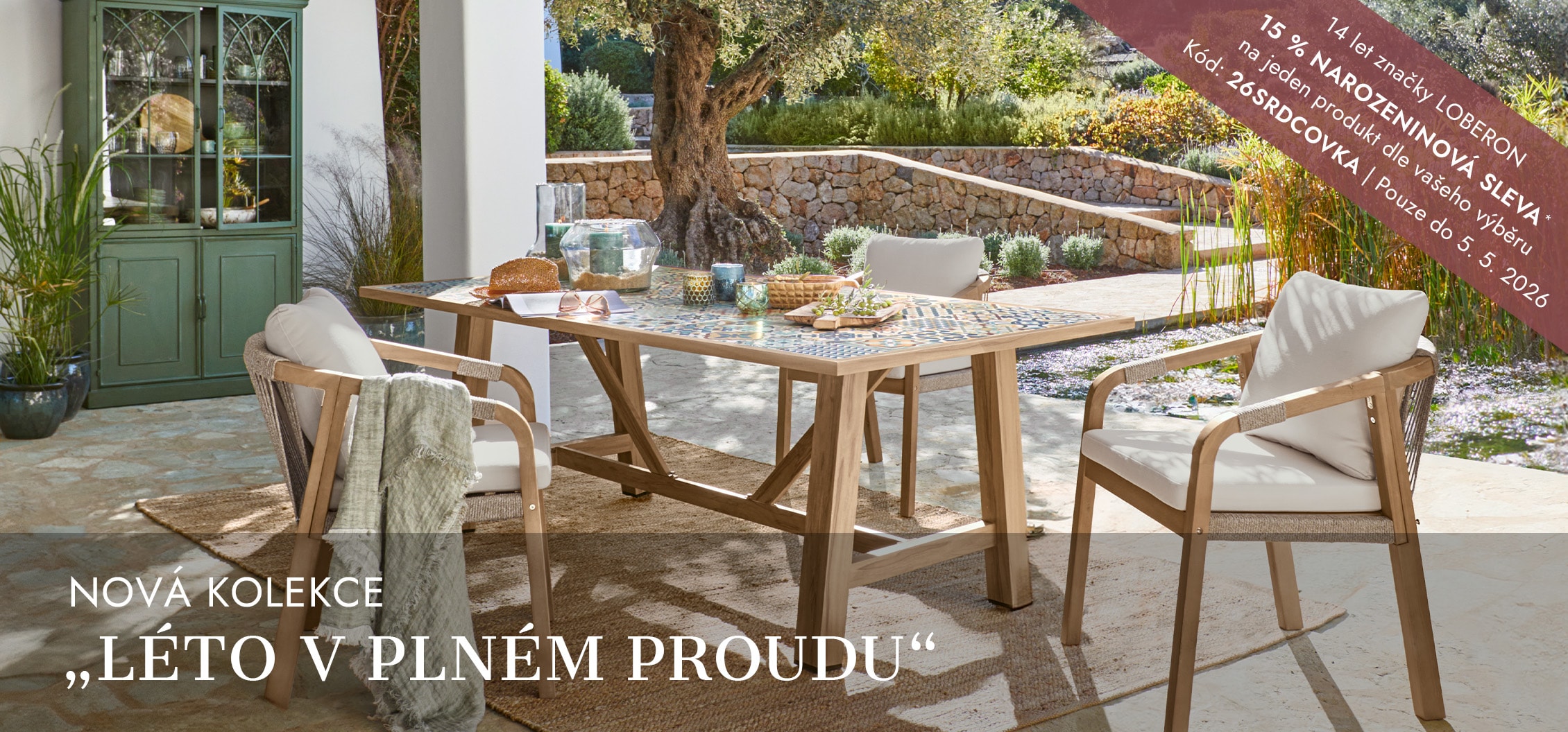 Zahradní nábytek s dřevěným stolem a židlemi s světlými polštáři na slunné terase