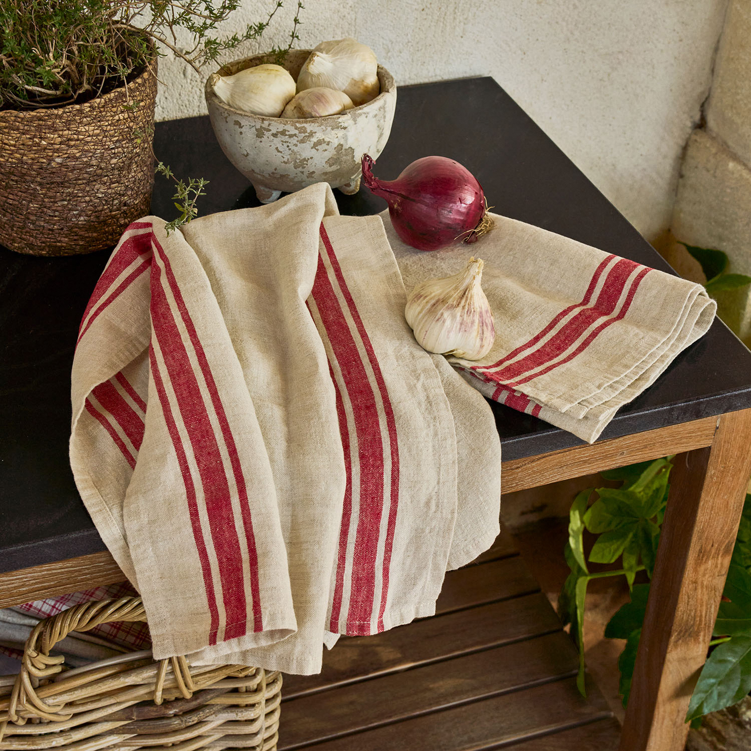 Béžová lněná kuchyňská utěrka s červenými pruhy na dřevěném stole s černou deskou