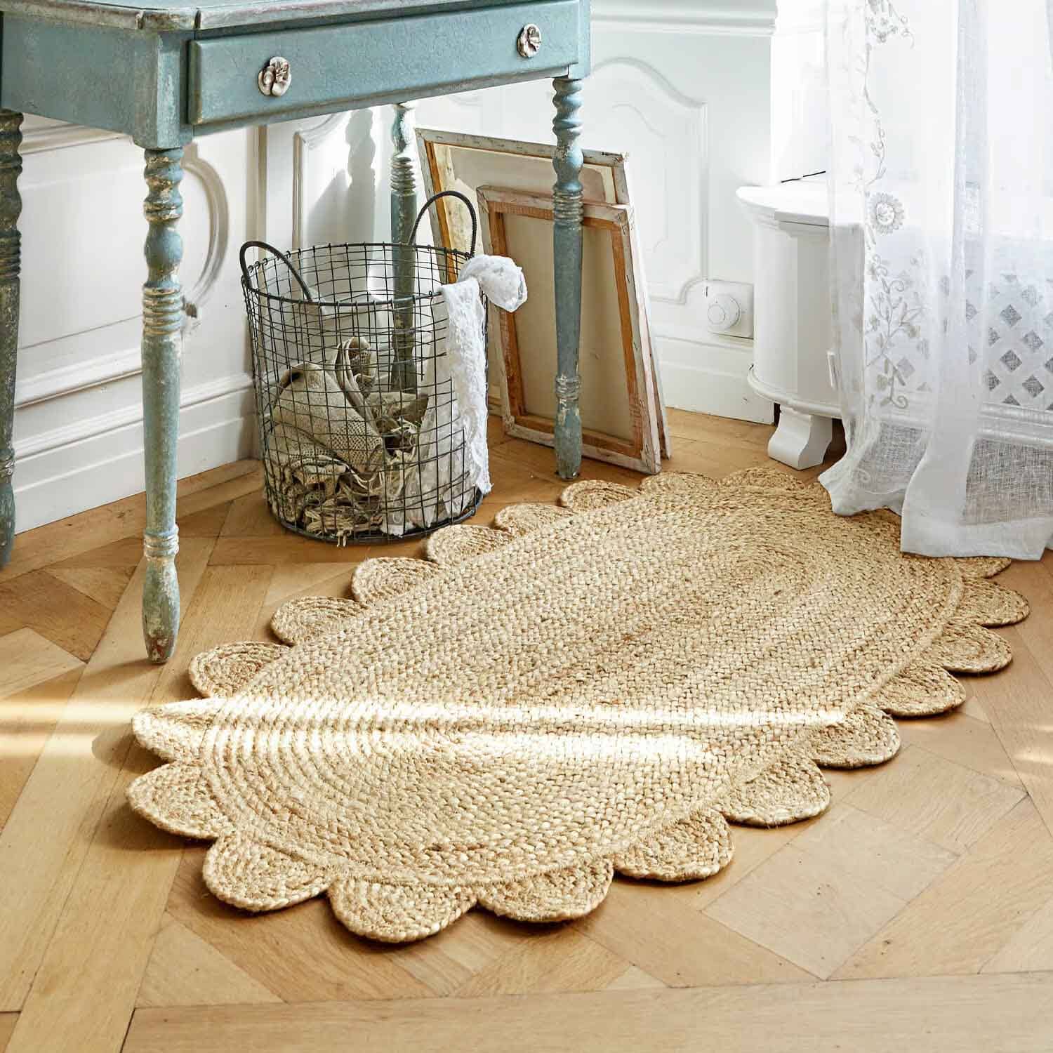 Oválný koberec z přírodní juty s ozdobným vroubkovaným okrajem na světlé dřevěné podlaze