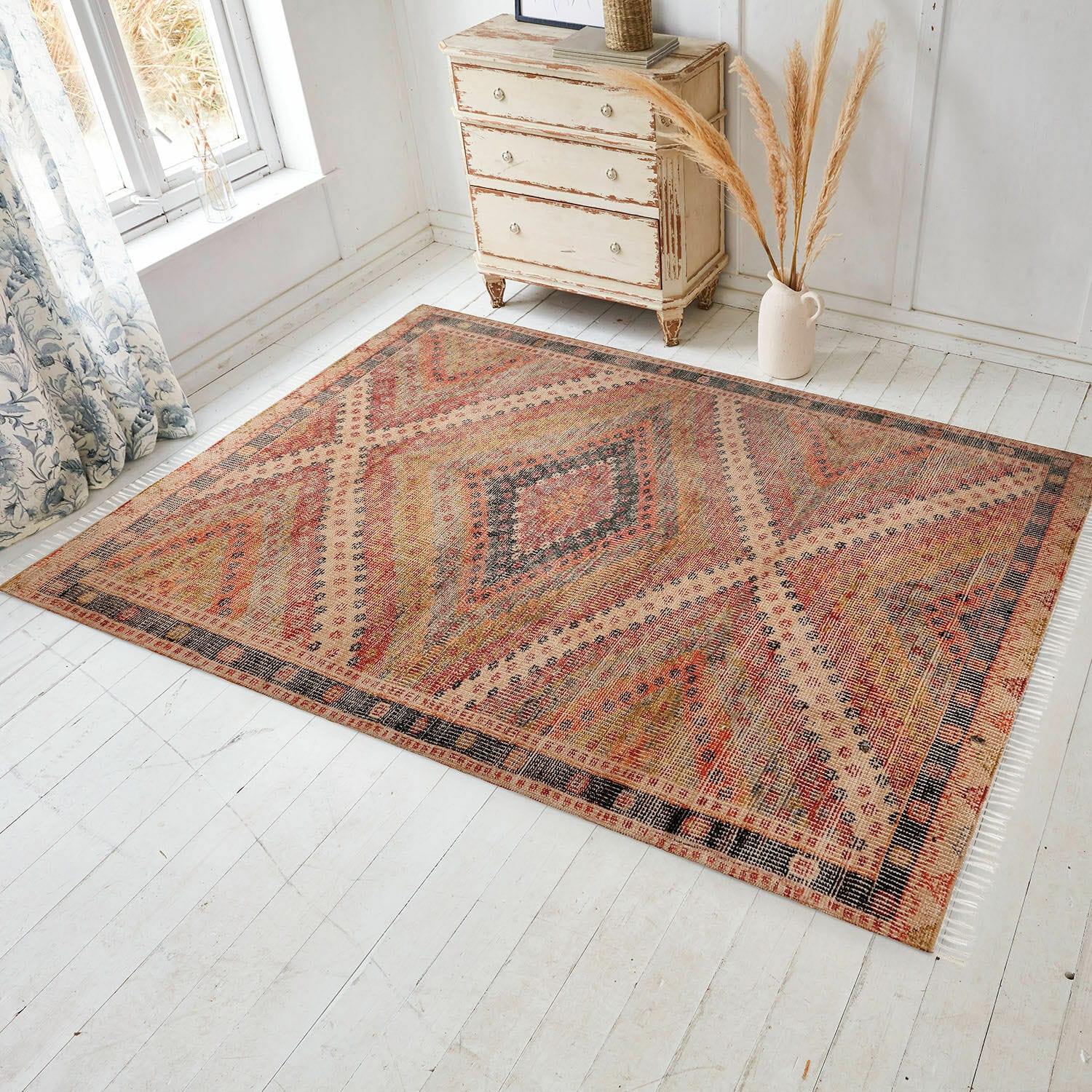 Koberec na doma i na ven Mildura Koberec s geometrickým vzorem v teplých červených a béžových odstínech na světlé podlaze