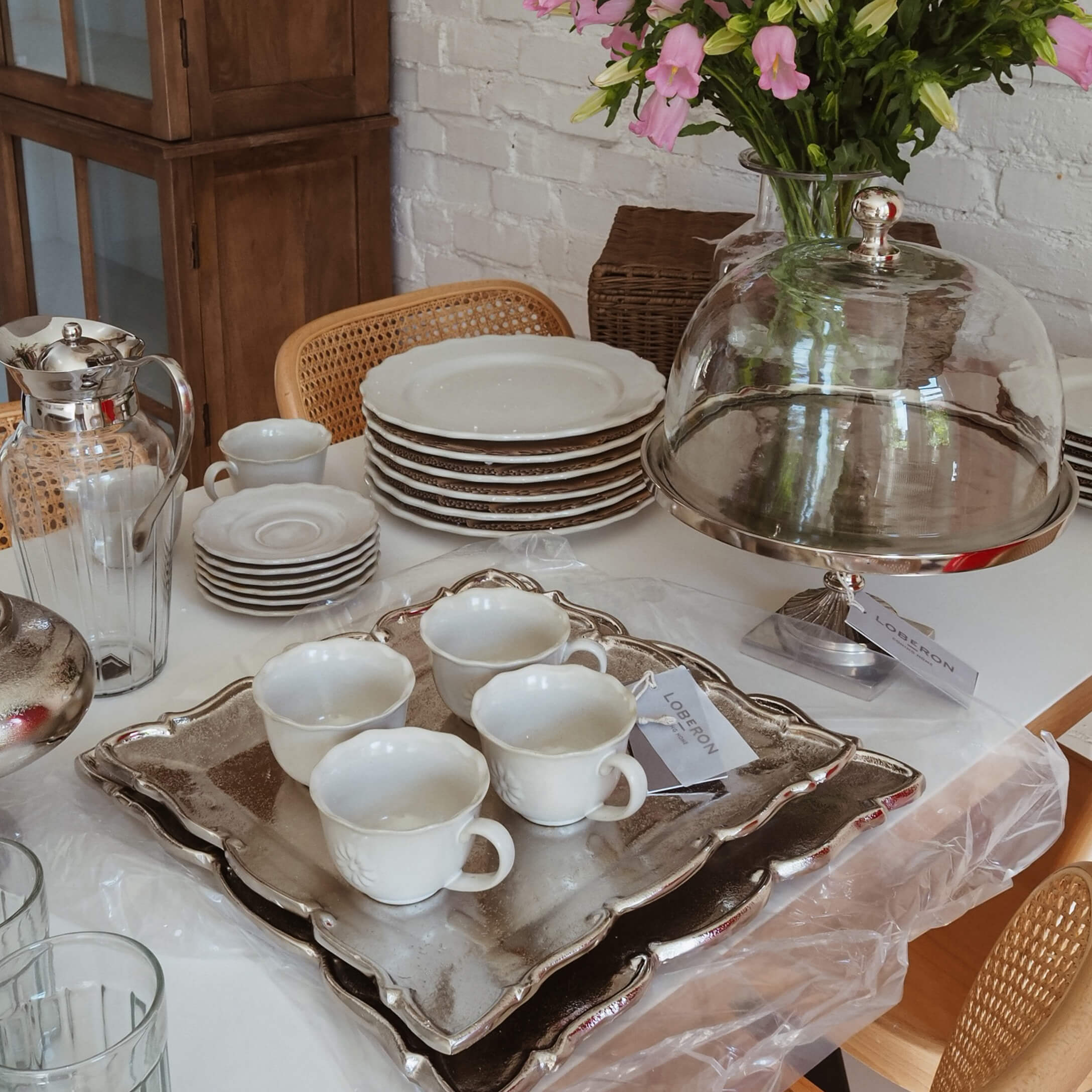 Bílý porcelán s šálky a talíři na stříbrném podnosu, dekorace stolu ve stylu slow living