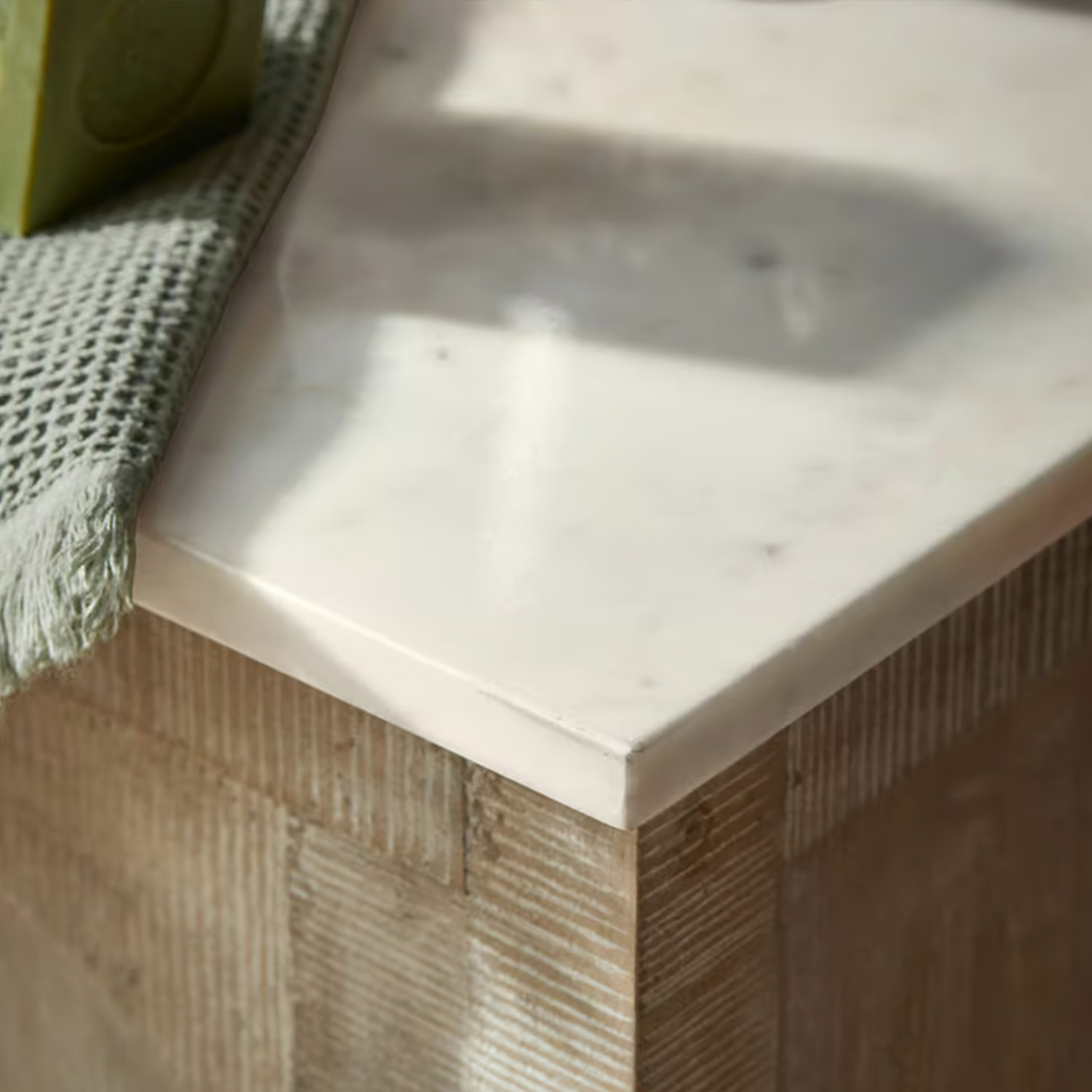 Bílá mramorová deska na dřevěné podnoži s zeleným textilním ručníkem, moderní nábytek