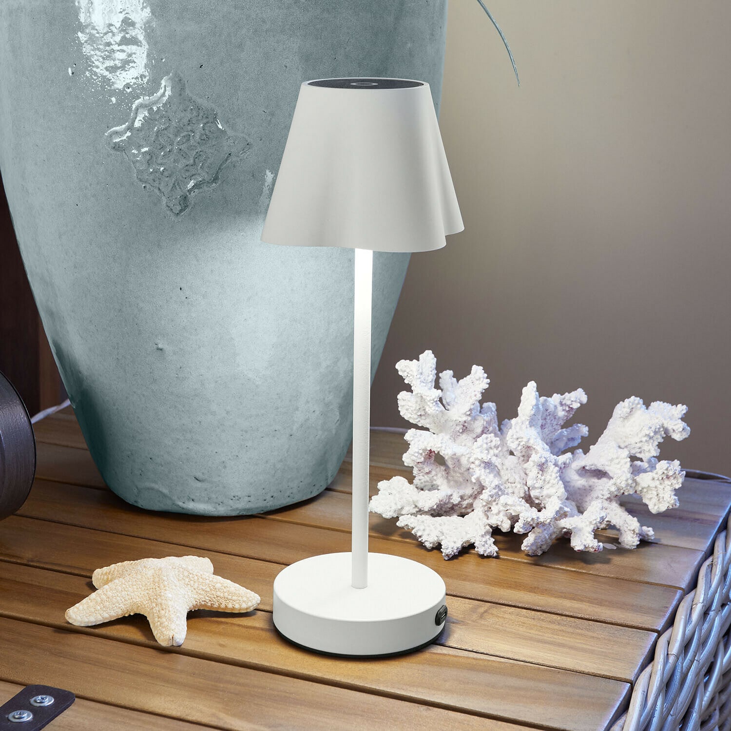 Bílá kovová stolní lampa s lampou na dřevěném stole s mořskou dekorací