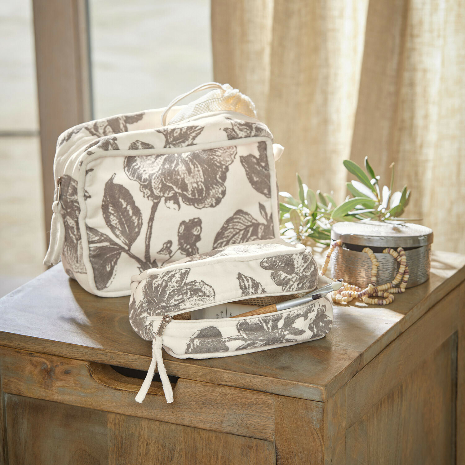 Sada dvou bavlněných kosmetických taštiček v krémové barvě se šedým květinovým vzorem na dřevěném stole