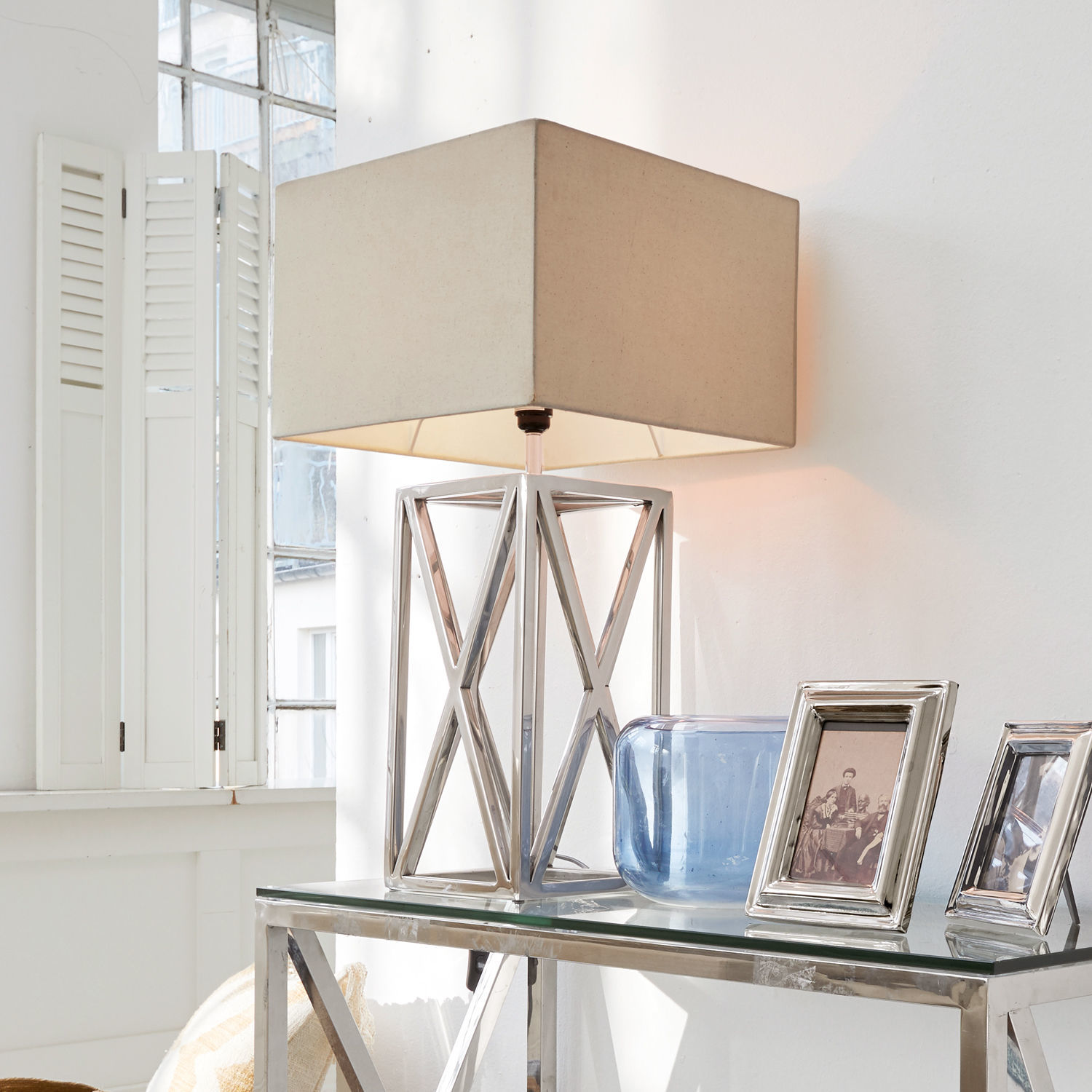 Stolní lampa Foix Moderní stolní lampa s kovovou základnou a béžovým stínidlem na skleněném stole v světlém interiéru