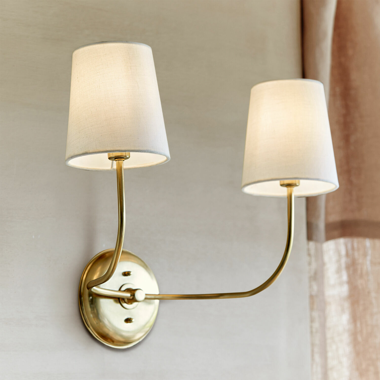 Nástěnná lampa Plainfield Dvojitá nástěnná lampa z mosazi s krémovými textilními stínidly pro interiérové osvětlení