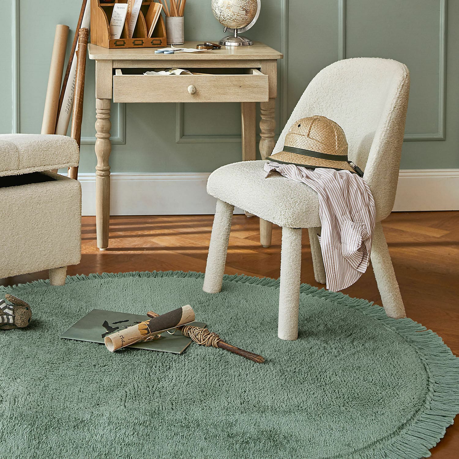 Koberec Ivalex Krémová čalouněná židle na zeleném kulatém koberci s třásněmi v místnosti s dřevěným stolem