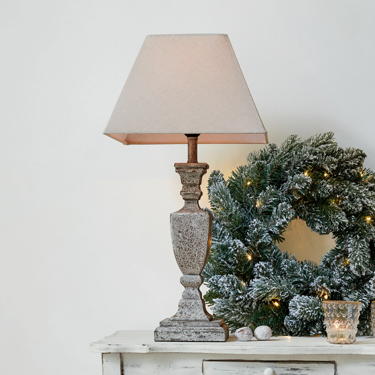 Stolní lampa Gorham Stolní lampa z kamene v béžové barvě s textilním stínidlem vedle vánočního věnce se zelenými větvemi a světýlky