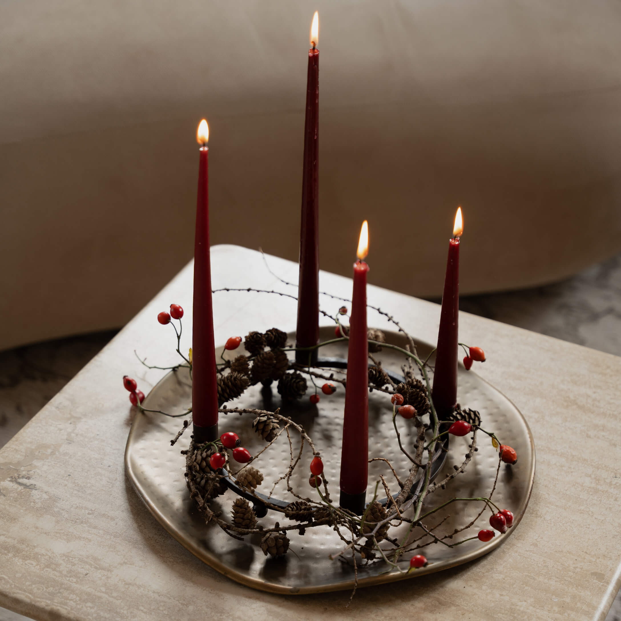 Adventní věnec s červenými svíčkami, šiškami a červenými bobulemi na kovovém podnosu
