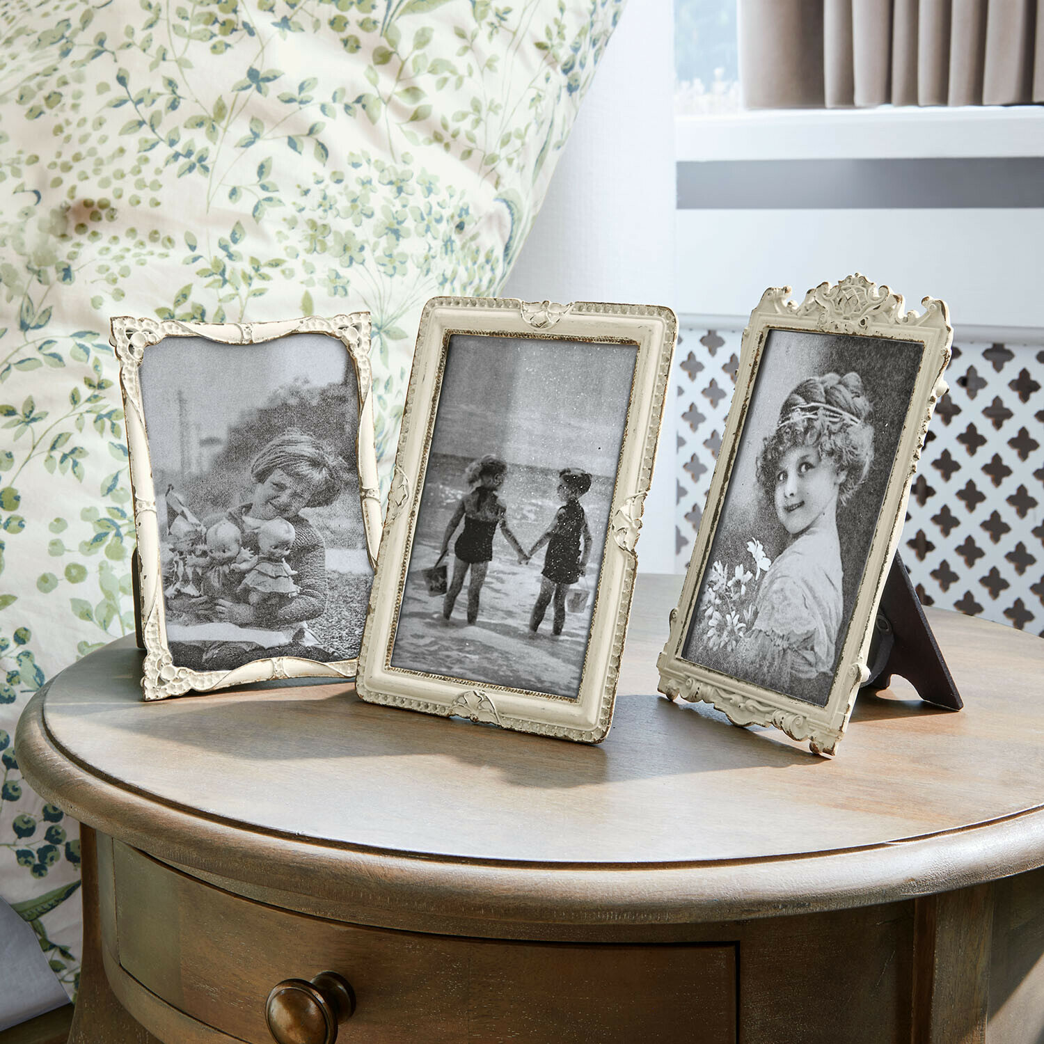 Fotorámečky, 3dílná sada Jorivex Tři ozdobné vintage fotorámečky na dřevěném stolku v světlé místnosti