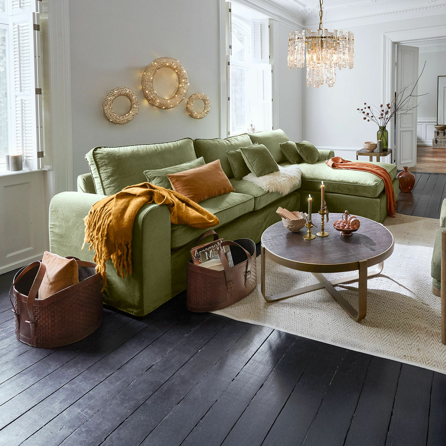 Pohodlná zelená rohová pohovka z měkkého materiálu v obývacím pokoji s tmavou dřevěnou podlahou a dekorativním osvětlením