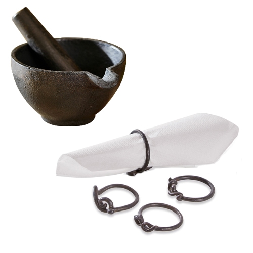 Černý litinový hmoždíř s tloučkem a kovové černé kroužky na ubrousky do kuchyně