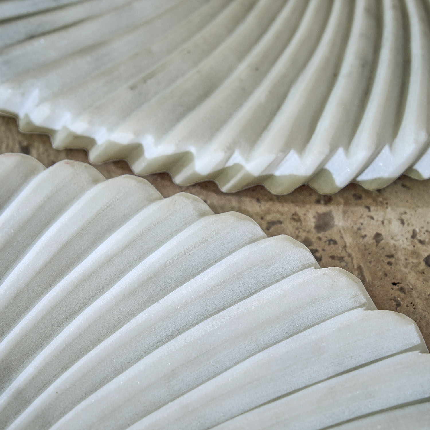 Bílé keramické dekorativní talíře s vroubkovaným vzorem na kamenném povrchu, ozdoba stolu