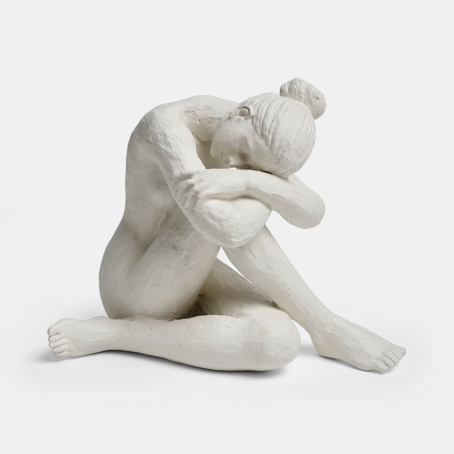 Bílá socha ženy sedící s hlavou na sepjatých pažích, dekorace z sádry