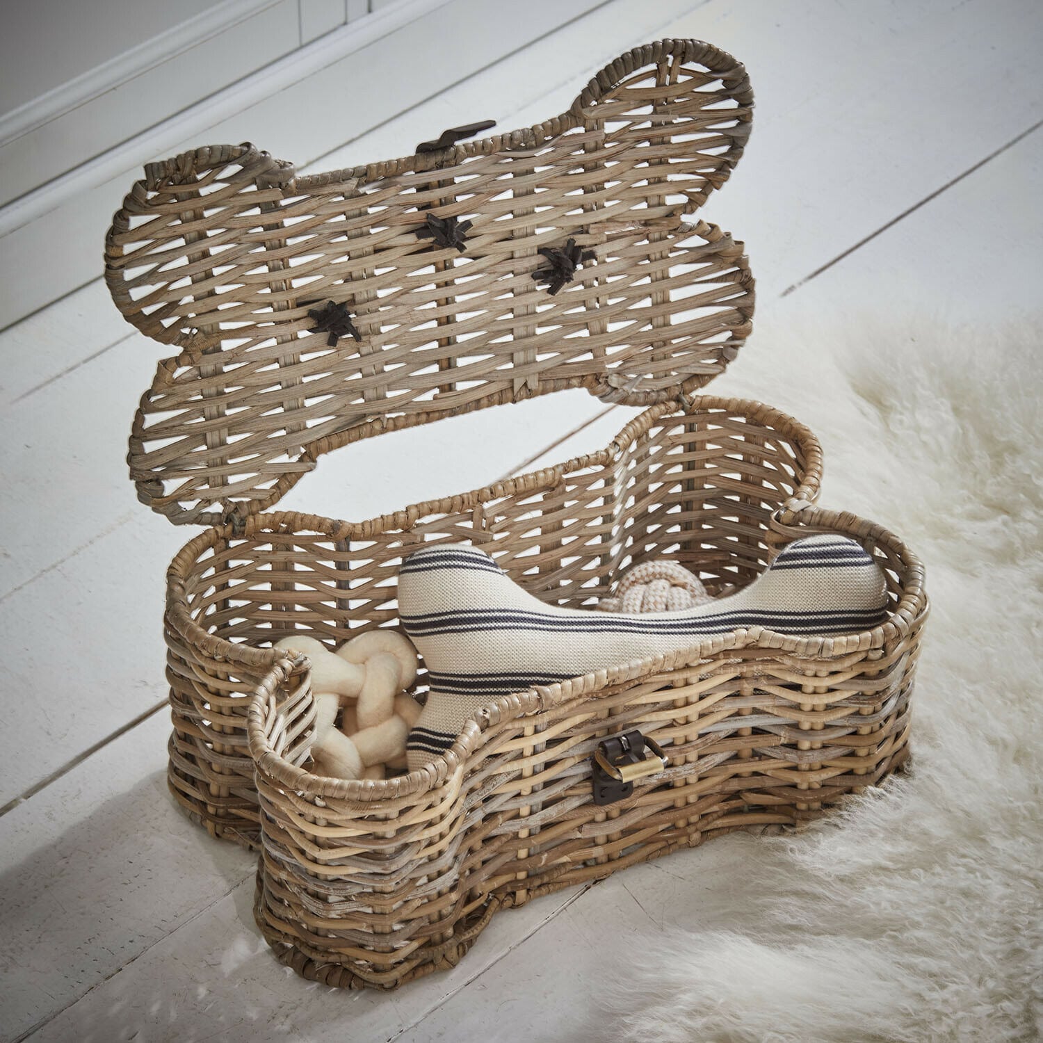 Úložný box na hračky Nuzzlea Ratanový koš ve tvaru kosti s psími hračkami v přírodní barvě na bílé podlaze