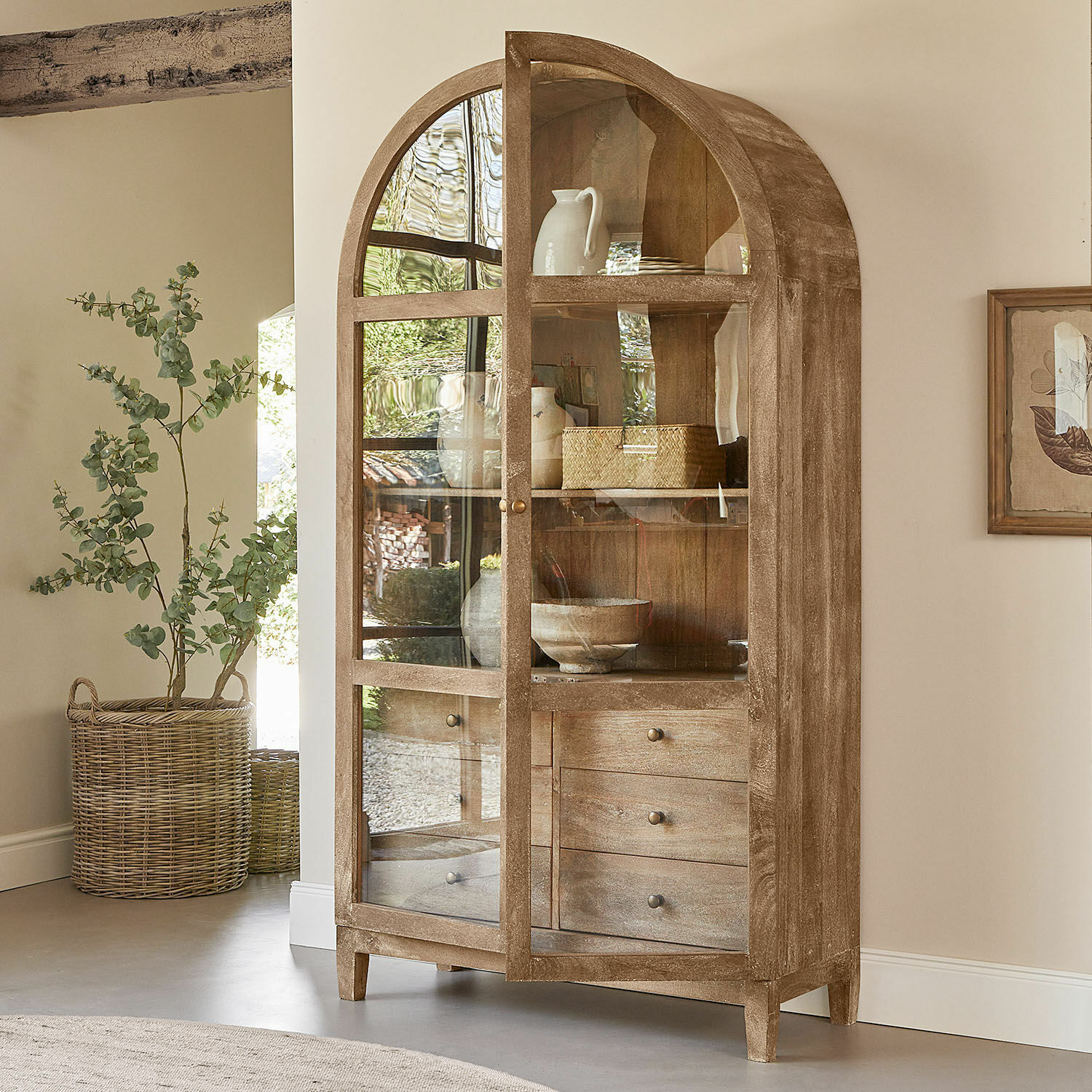 Vitrína Winscombe Dřevěná vitrína s prosklenými dveřmi a třemi zásuvkami v přírodní barvě dřeva do obývacího pokoje