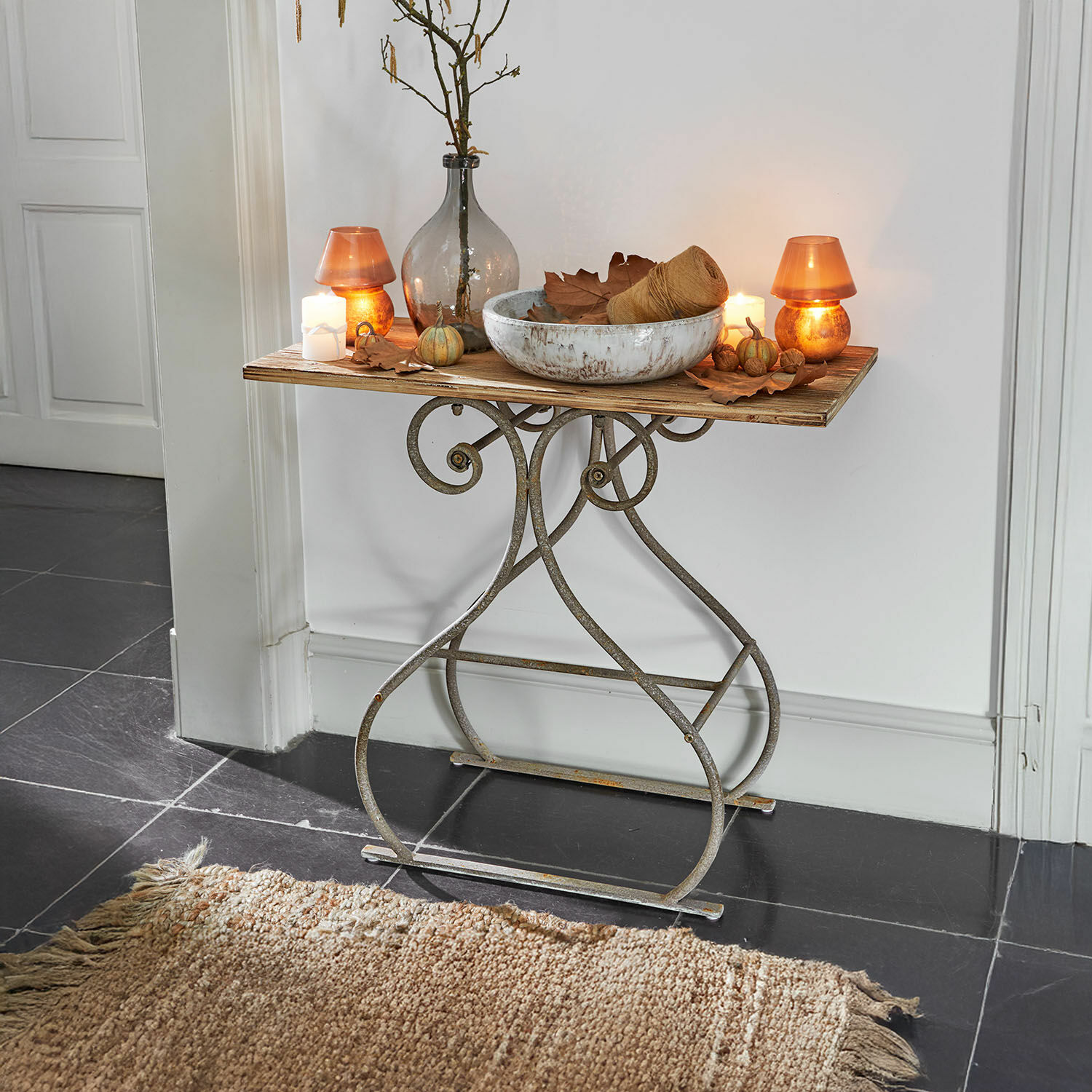 Stolek s kovovou podnoží a dřevěnou deskou, ozdobený svíčkami a vintage váza