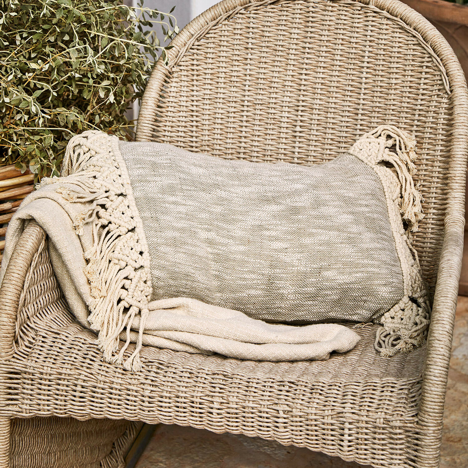 Béžová deka s třásněmi na proutěném křesle, útulný bytový doplněk a dekorace