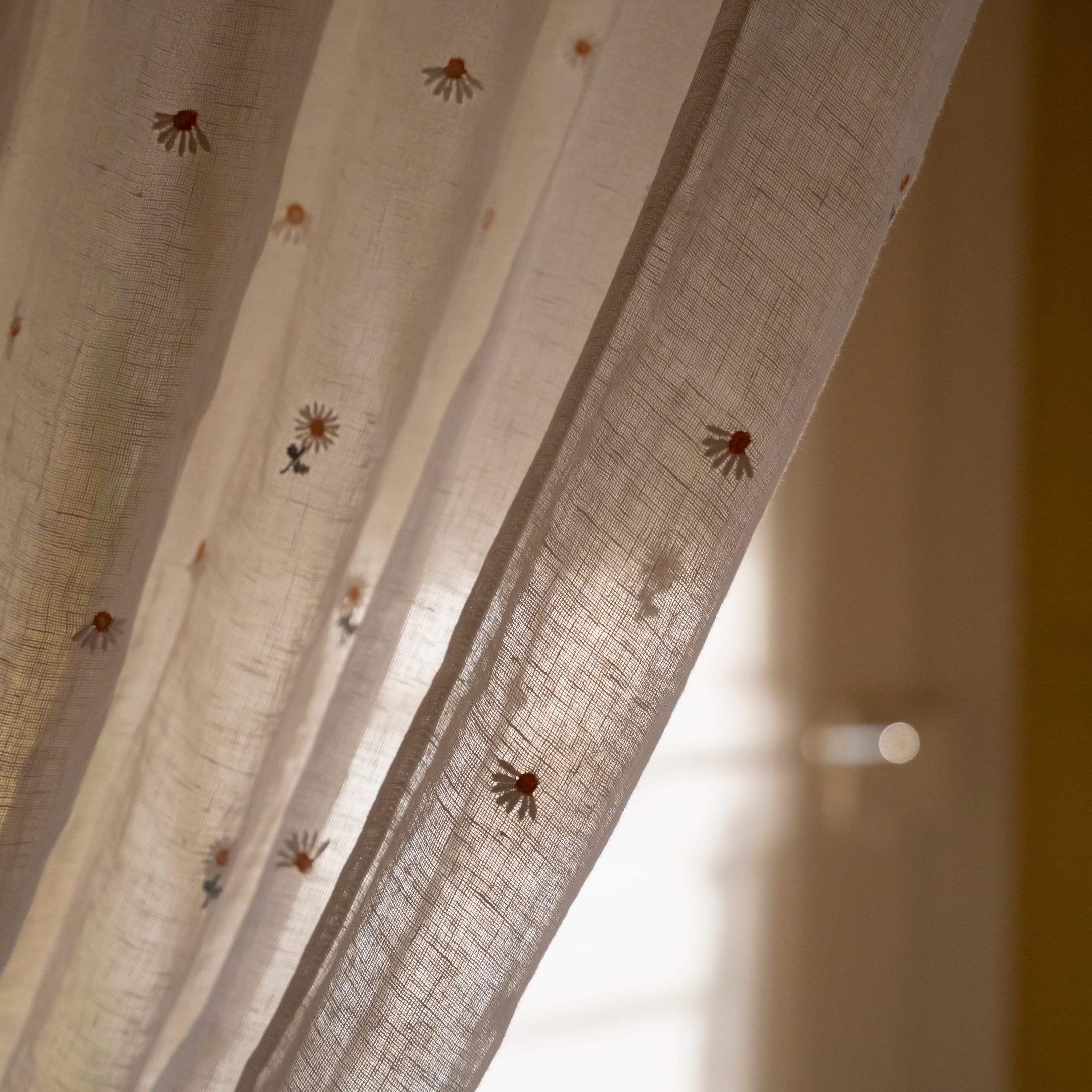 Průsvitná bílá záclona s jemnou výšivkou sedmikrásek, lehká látka na dekoraci oken