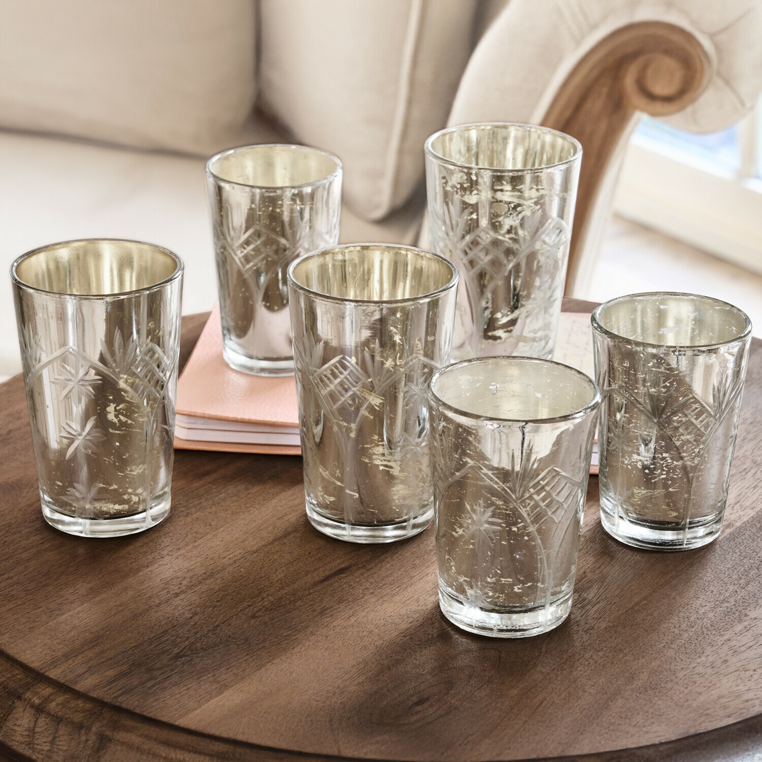 Sada šesti skleněných svícnů s rytým vzorem a stříbrným povrchem na dřevěném stole