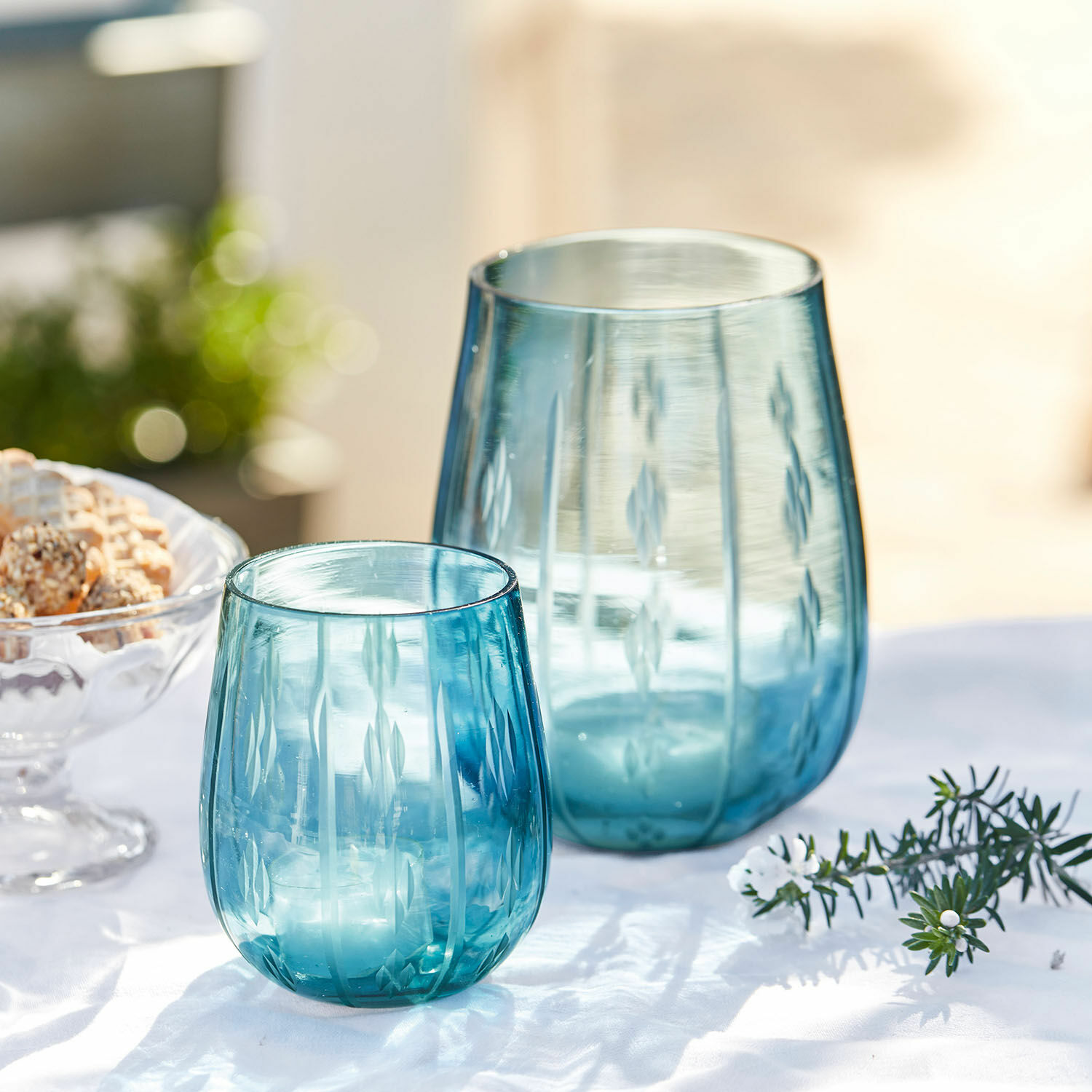 Dva modré skleněné svícny s rytým vzorem na bílém pozadí, stolní dekorace