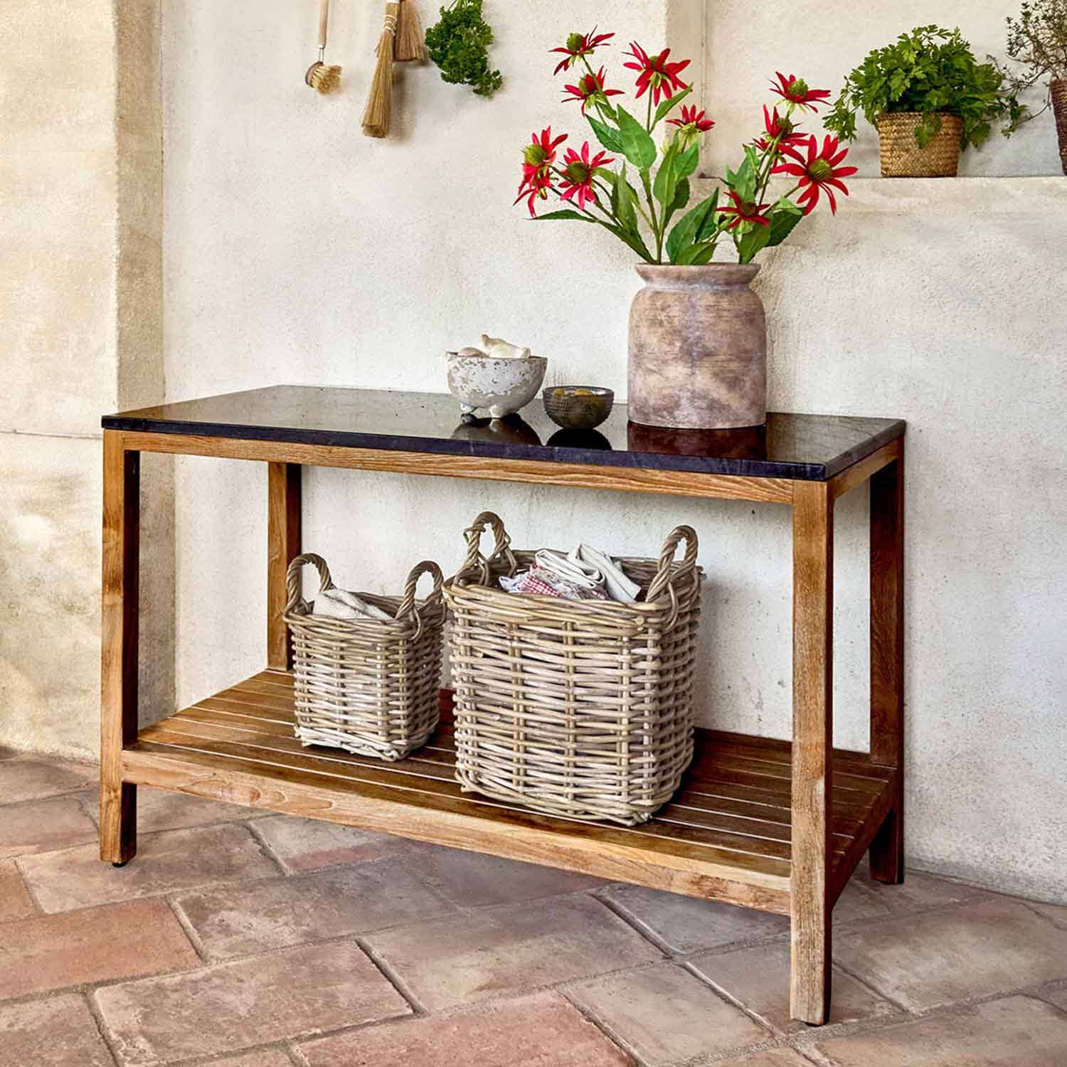 Dřevěný stolek s černou deskou a proutěnými koši, ozdobený červenými květy