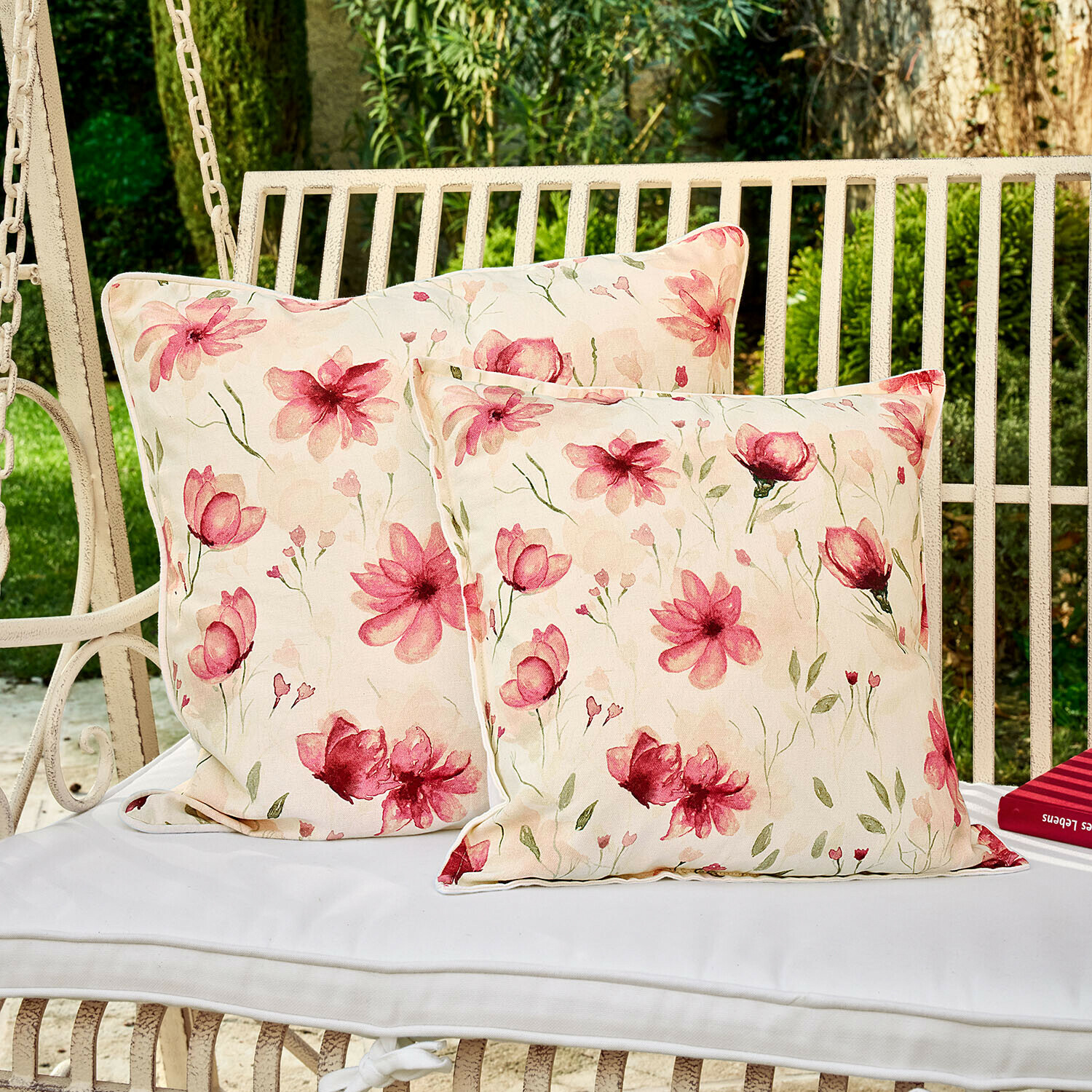 Dva dekorativní polštáře s květinovým vzorem na bílé zahradní houpačce, bavlněný materiál, světle růžové květy