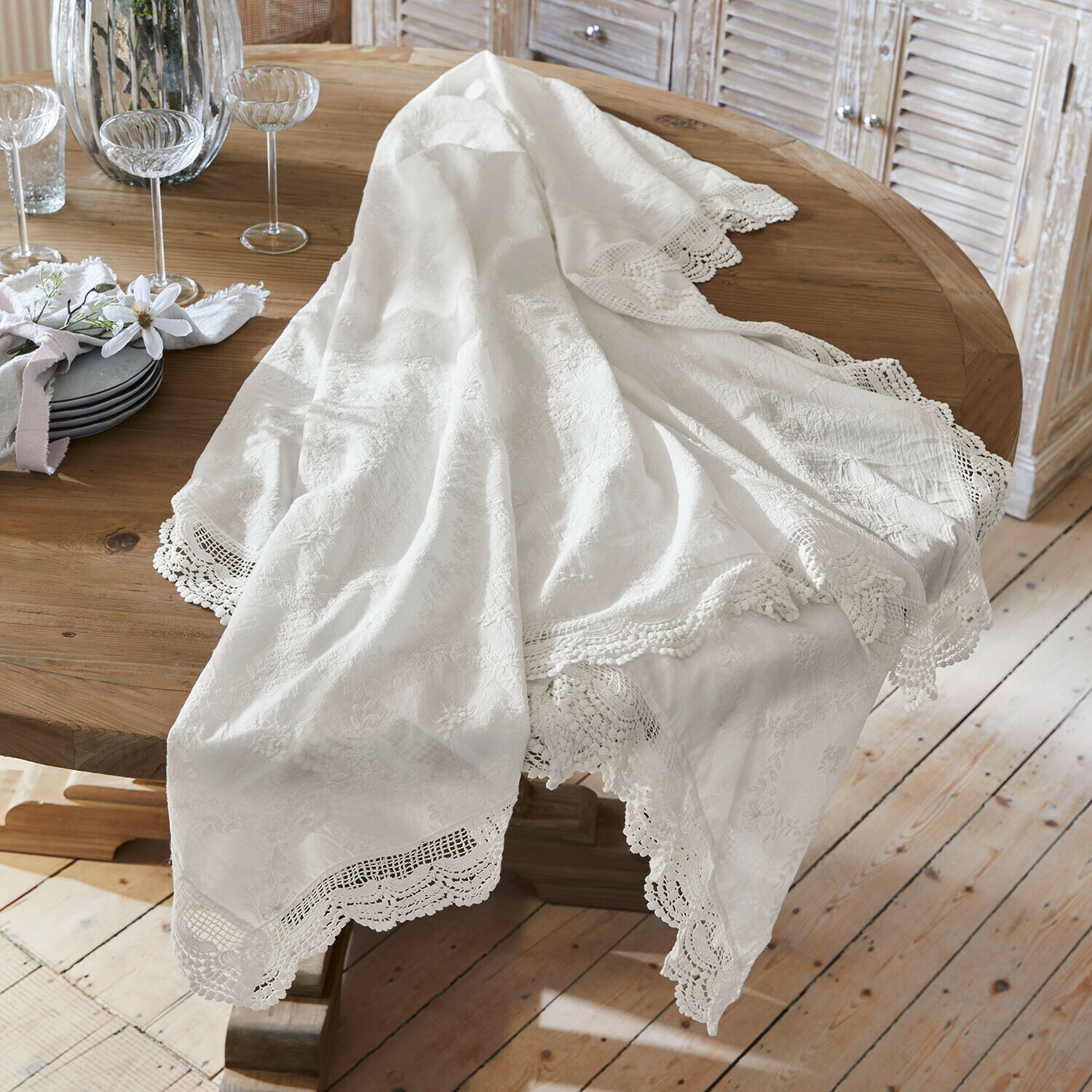 Bílý ubrus s krajkovým lemem na dřevěném stole, elegantní dekorace jídelny