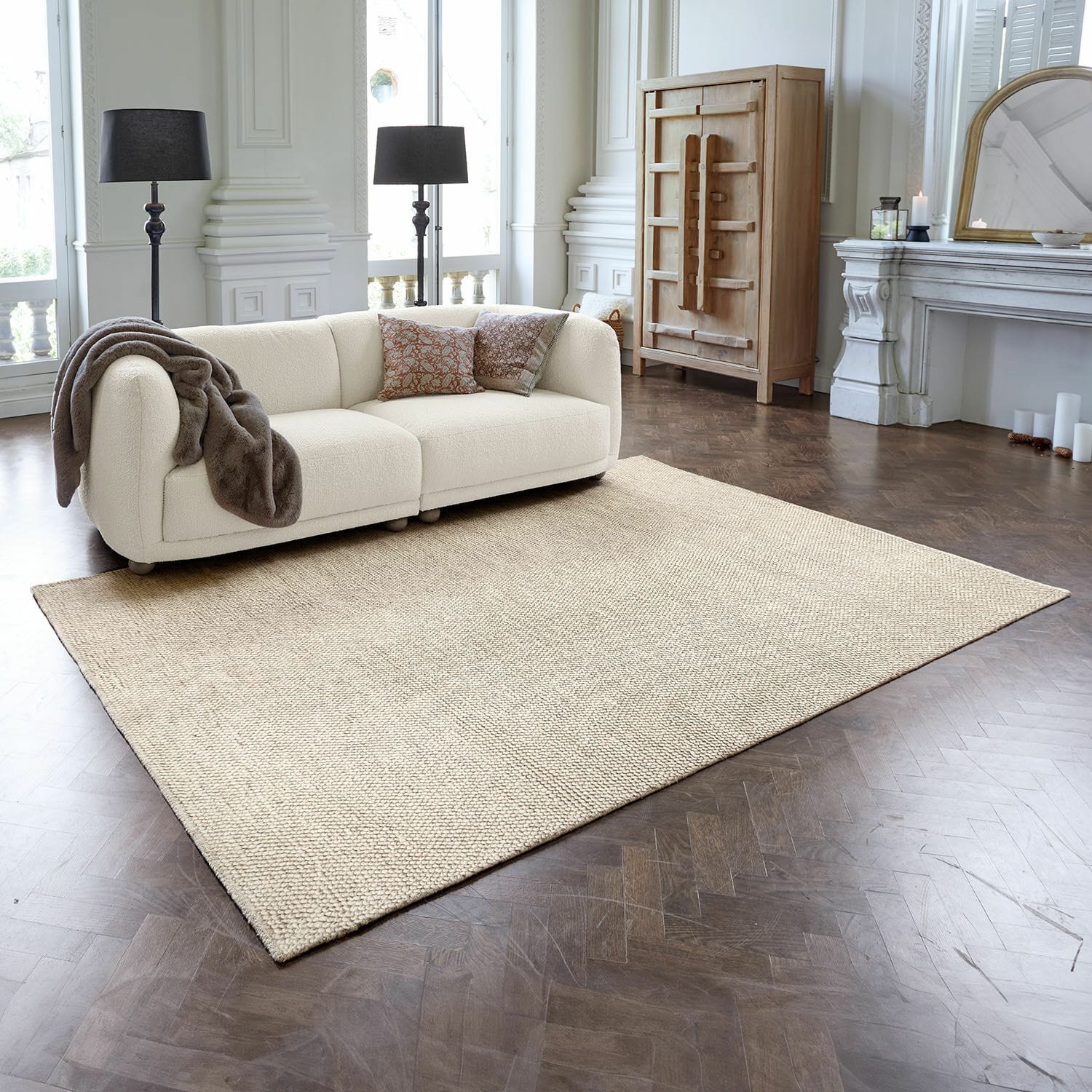 Koberec Coleman Béžový koberec z přírodního materiálu na tmavé dřevěné podlaze v elegantním obývacím pokoji s pohovkou