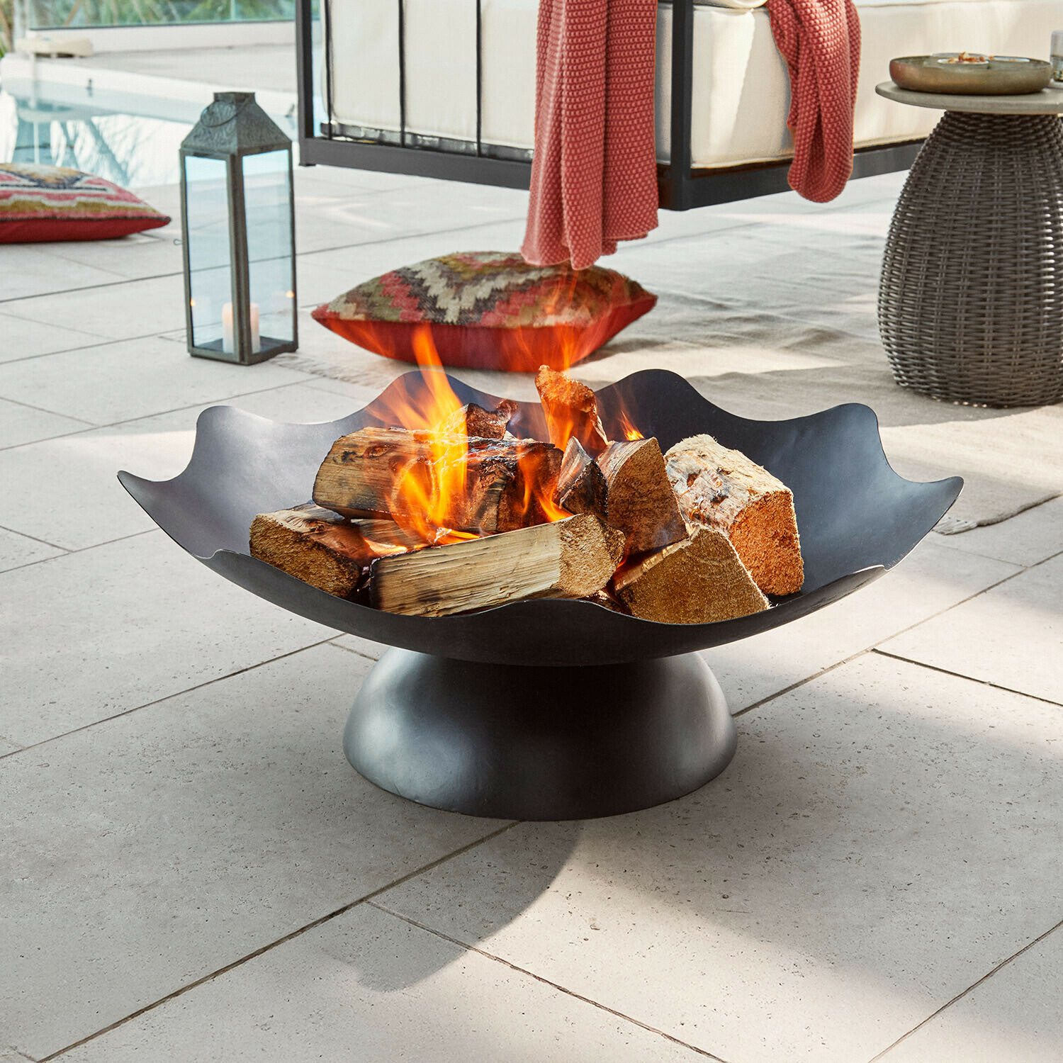 Černý kovový ohniště s hořícím dřevem na terase, vhodné pro zahradu a venkovní posezení