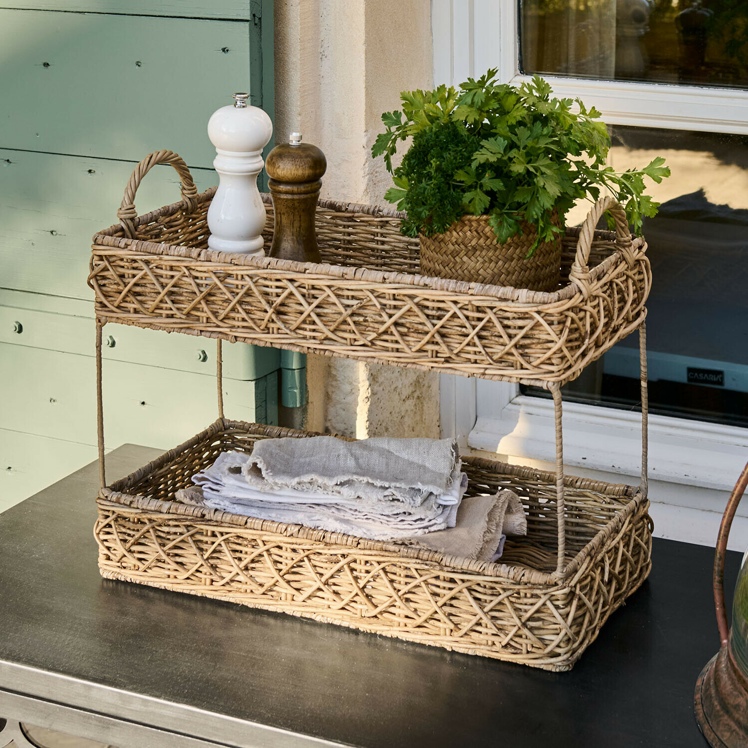 Dvoupatrový koš z přírodního ratanu s kořením a čerstvými bylinkami na stole