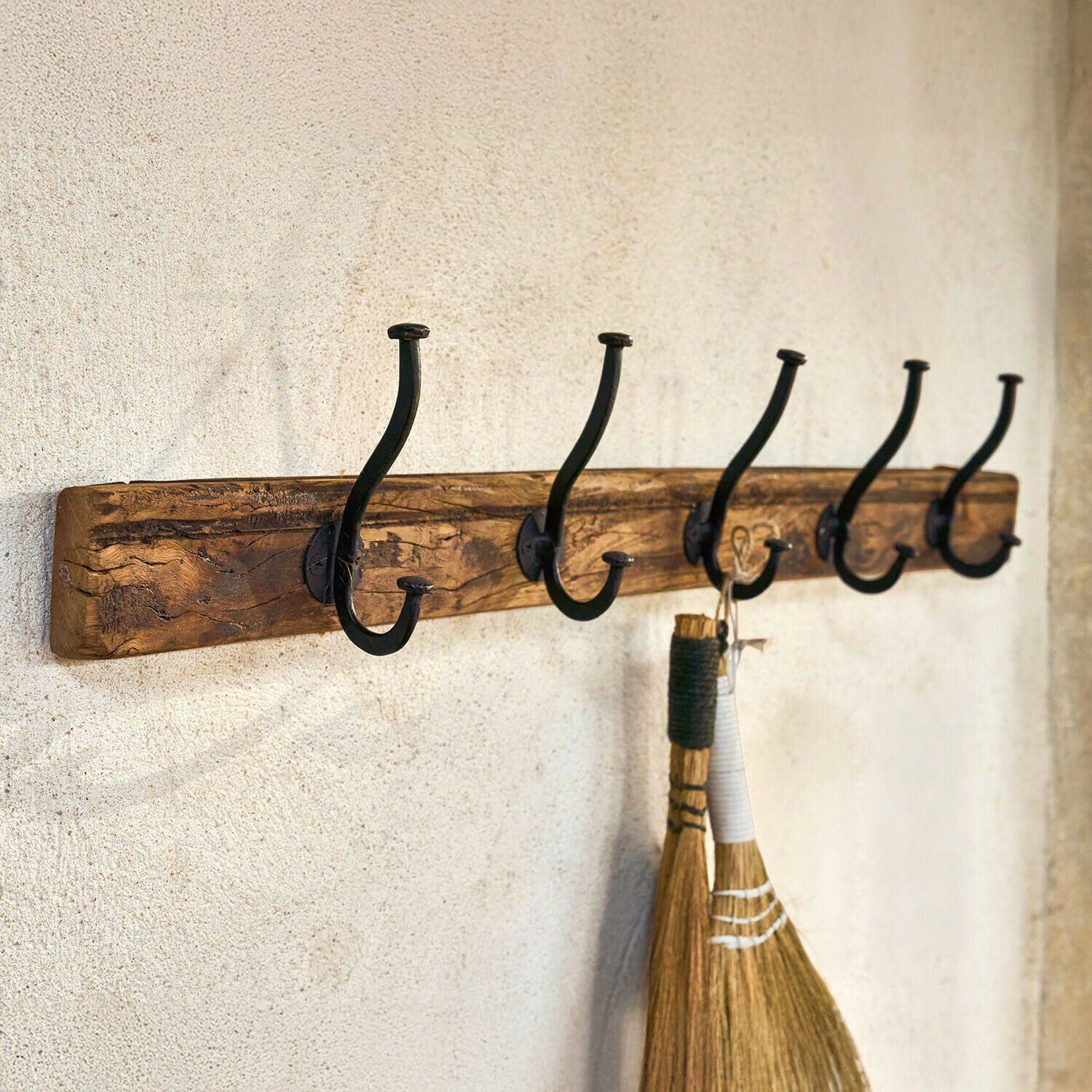 Rustikální nástěnný věšák ze dřeva s pěti černými kovovými háčky na zavěšení věcí